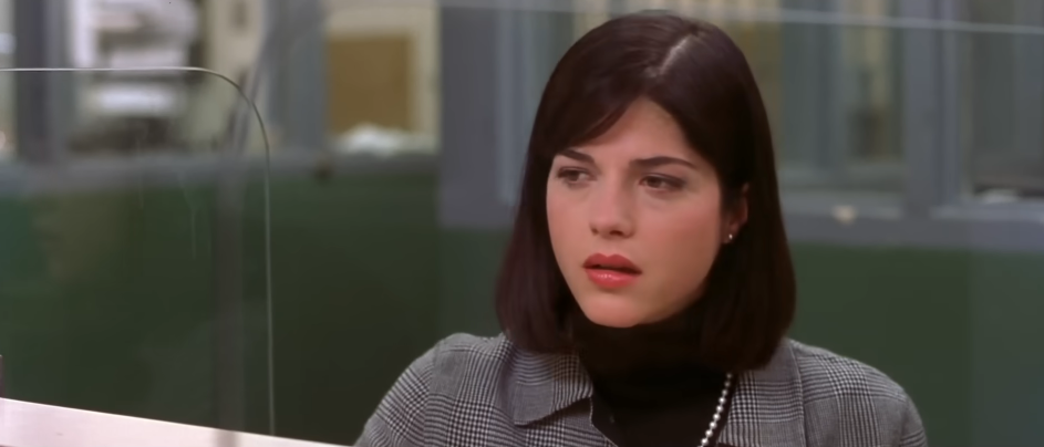 Selma Blair aparece interpretando a Vivian Kensington en una escena de la película de 2001 "Legalmente rubia". Con una expresión serena y atenta, lleva un suéter de cuello alto negro bajo un saco gris de cuadros Glen, con un collar de perlas, aretes pequeños y un bob castaño liso a la altura de los hombros con flequillo de lado. | Fuente: YouTube/Amazon MGM Studios