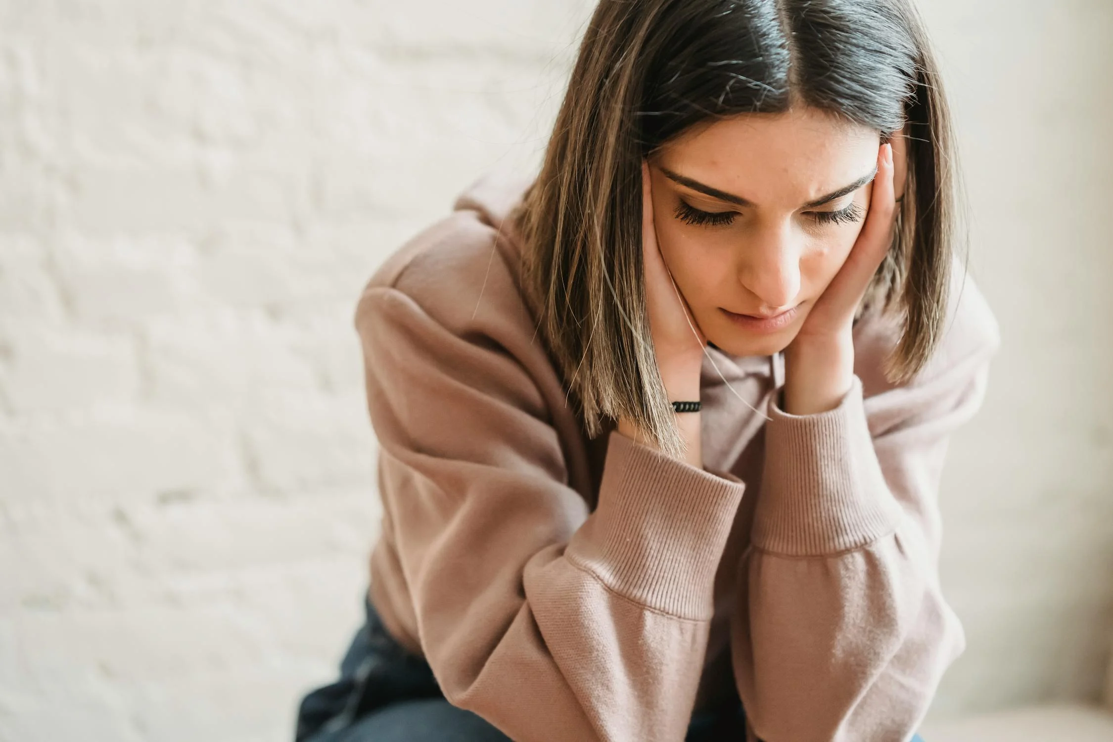 Una mujer triste sentada con los ojos cerrados ⏐ Fuente: Pexels