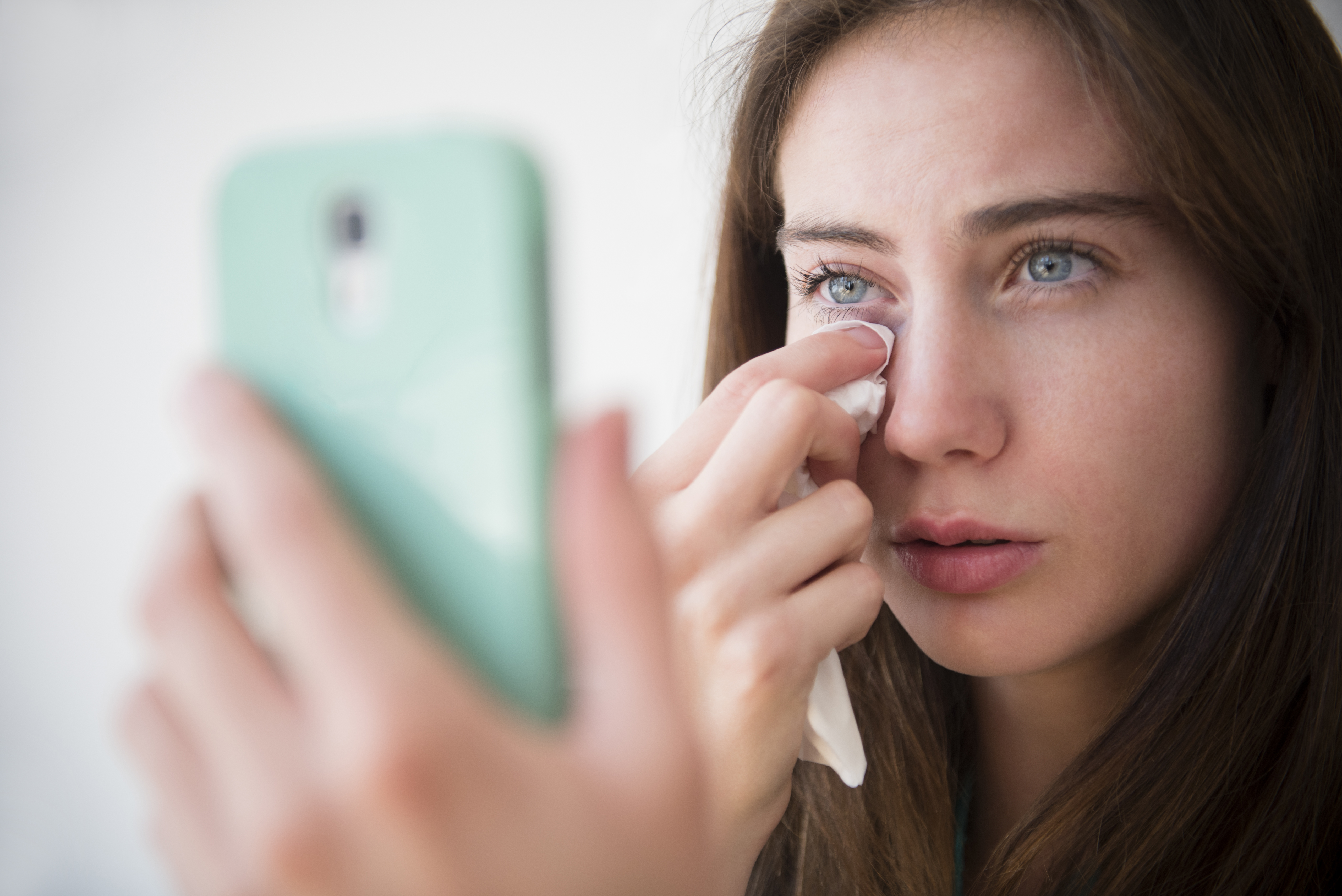 Una mujer se seca las lágrimas mientras habla por teléfono | Fuente: Getty Images