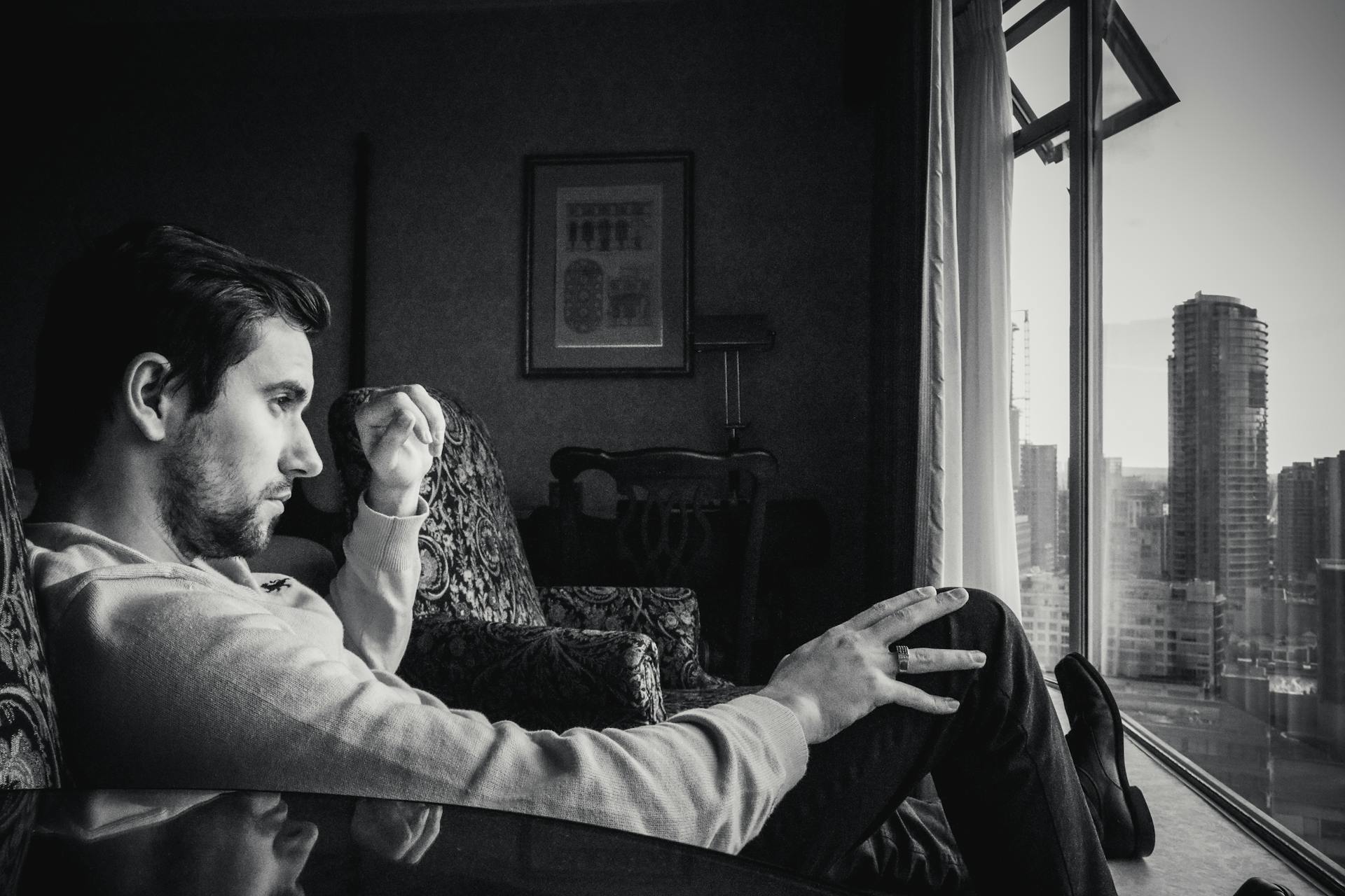 Foto en escala de grises de un hombre mirando por la ventana | Fuente: Pexels