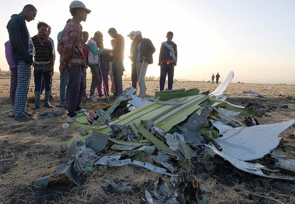 Hombres y jóvenes inspeccionan electrónicos recuperados de los restos del avión. Fuente: Getty Images