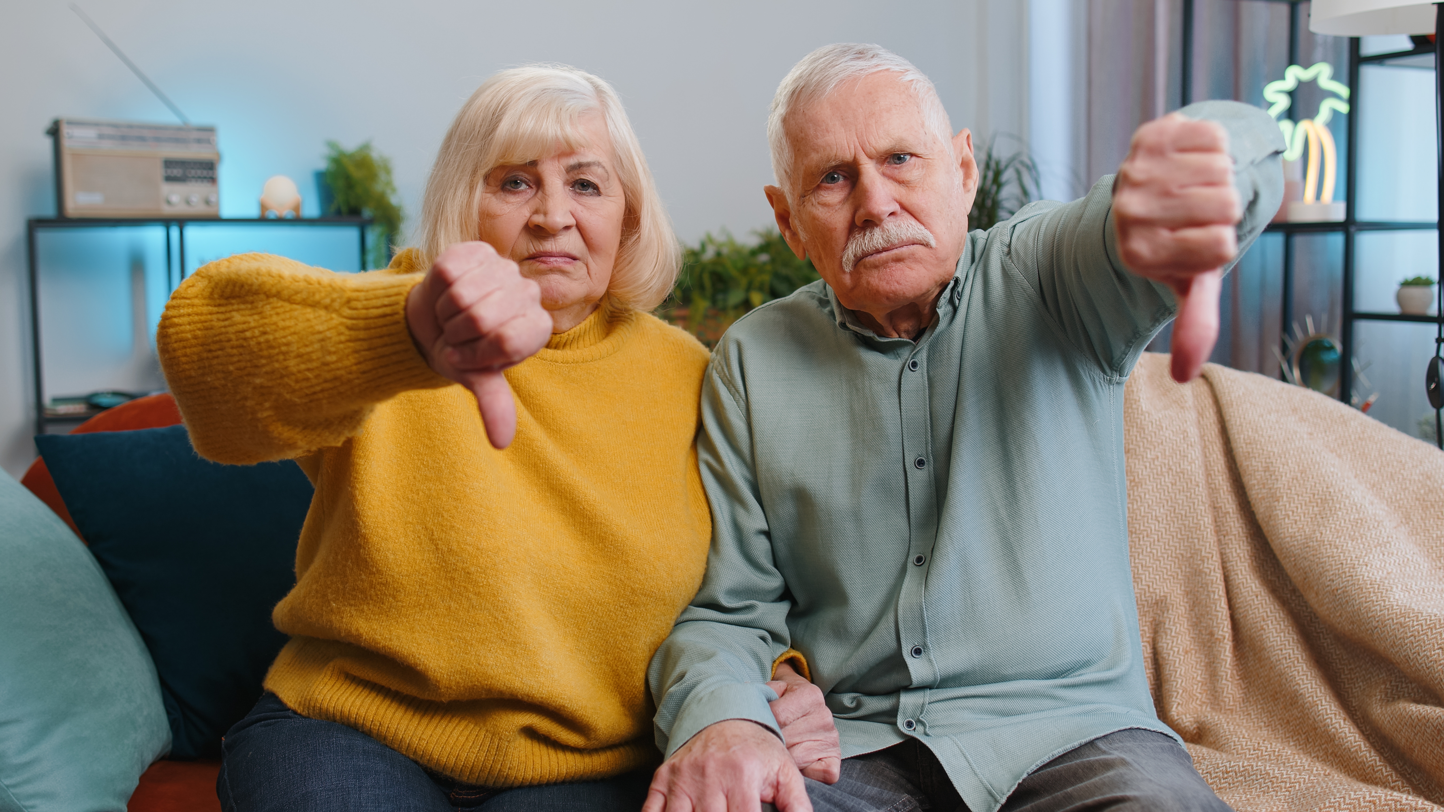 Pareja de ancianos mostrando el signo del pulgar hacia abajo | Foto: Shutterstock
