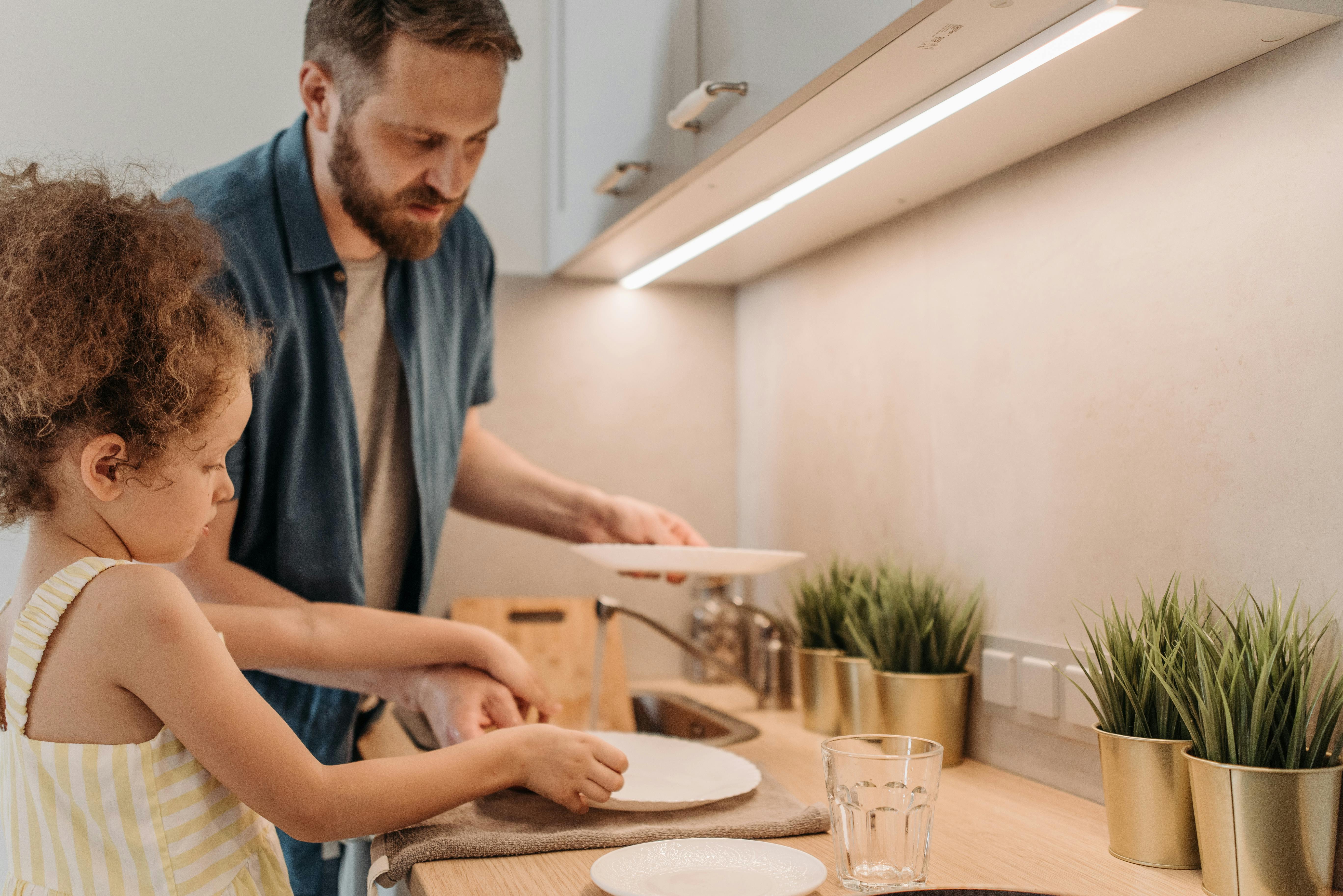 Un hombre lava los platos con su hija | Fuente: Pexels