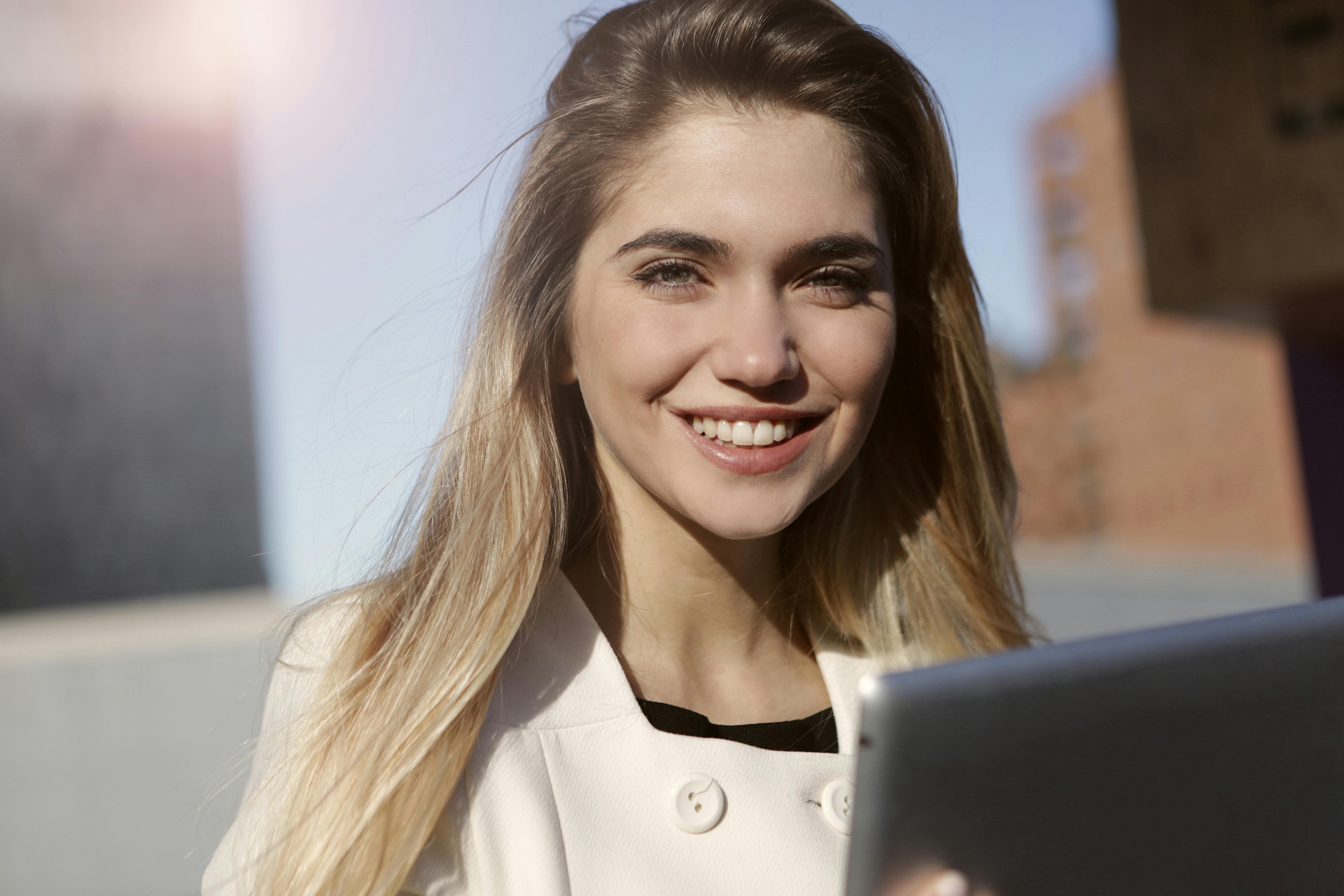 Mujer sonriente con camisa blanca abotonada | Foto: Pexels