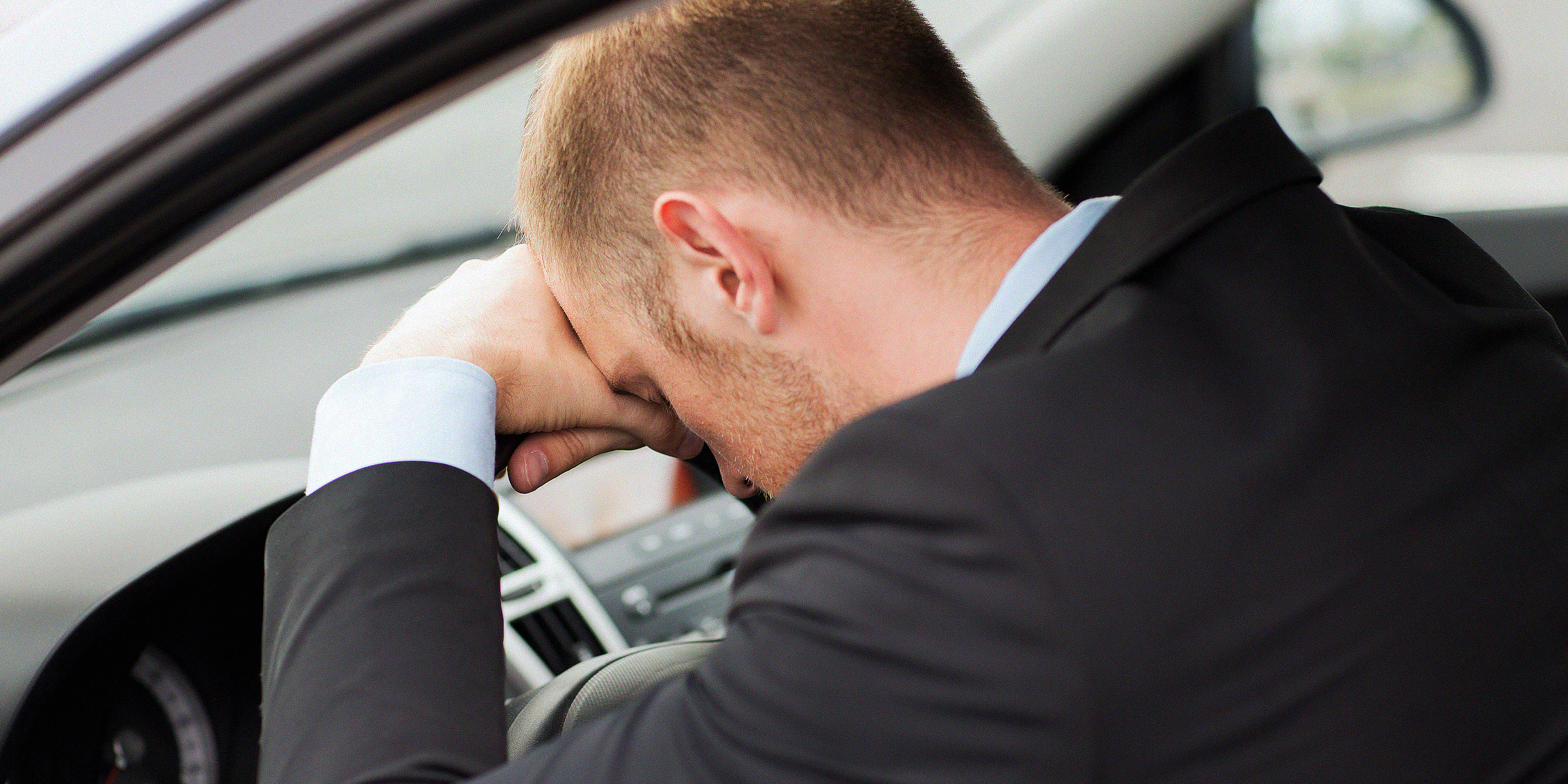 Hombre sentado en un automóvil con la cabeza en el volante | Foto: Shutterstock