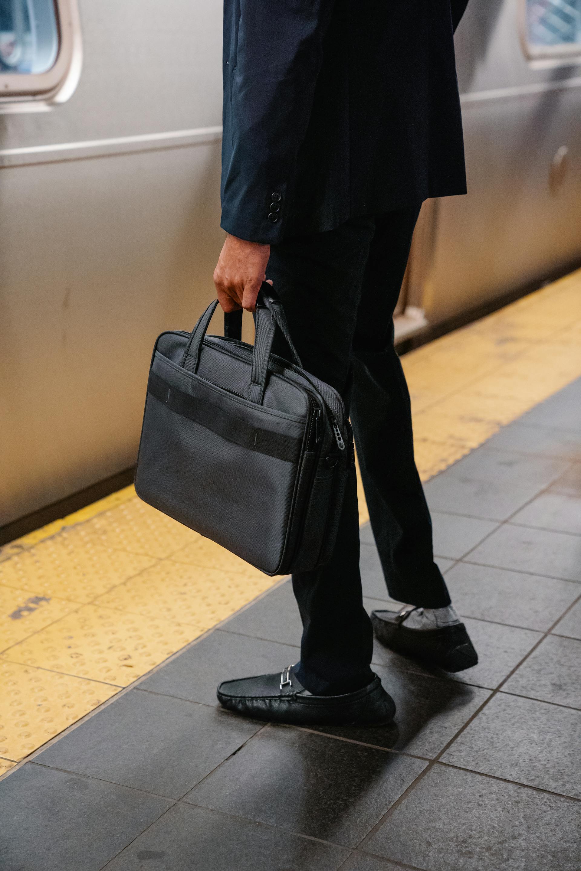 Primo piano di un uomo che trasporta una borsa in piedi su una banchina della metropolitana | Fonte: Pexels