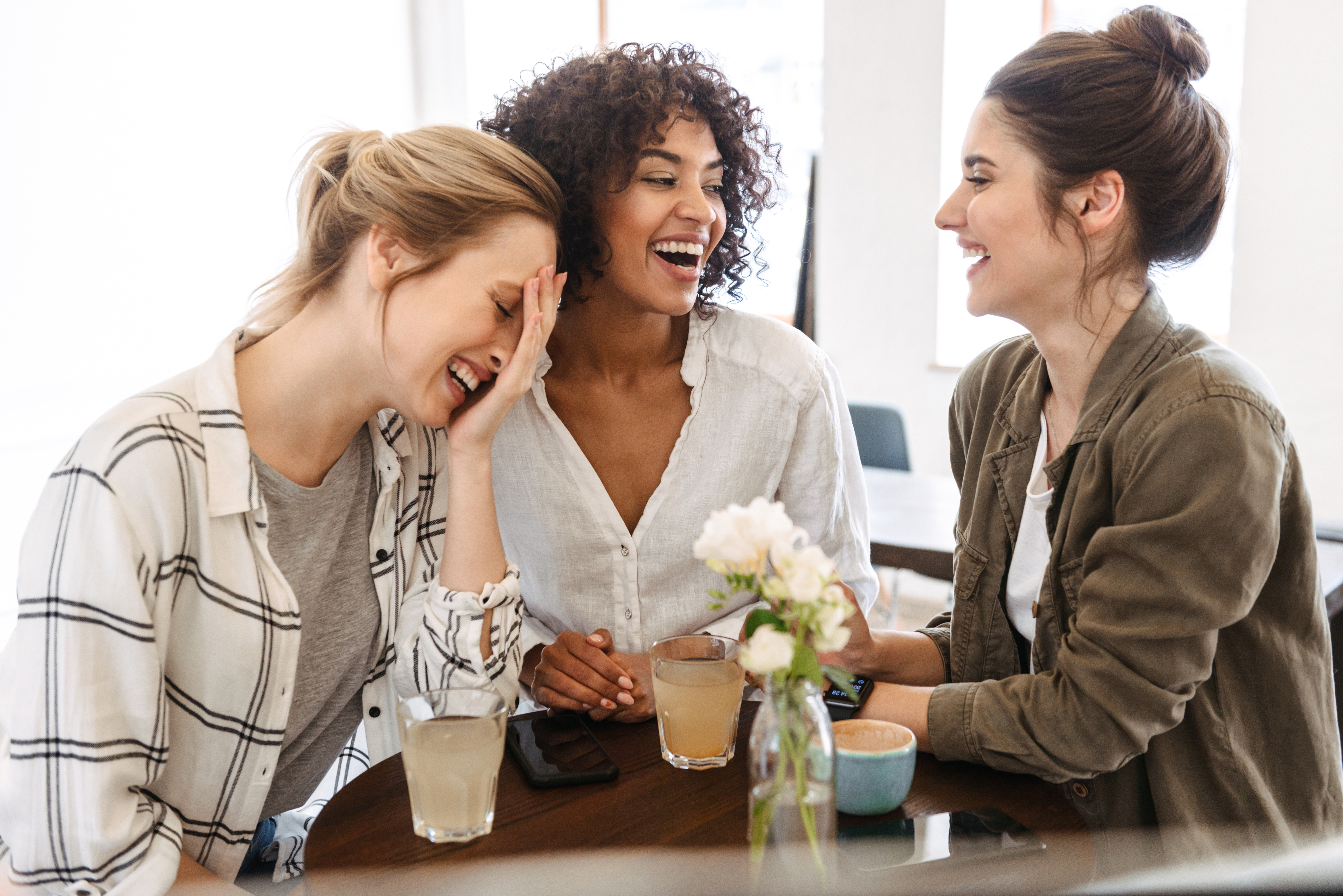 Tres mujeres felices disfrutando de un café y unas copas | Foto: Shutterstock