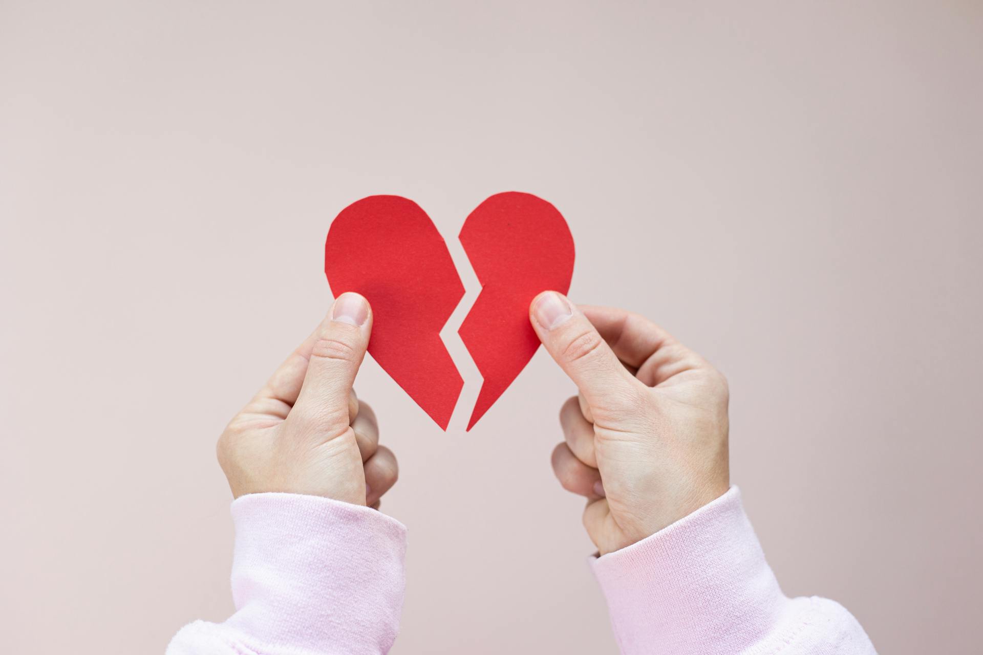 Una persona sostiene un corazón de papel rojo roto | Fuente: Pexels