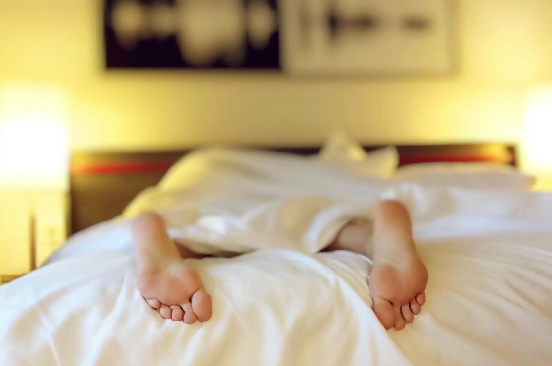 Una persona tumbada boca abajo en una cama | Foto: Pexels