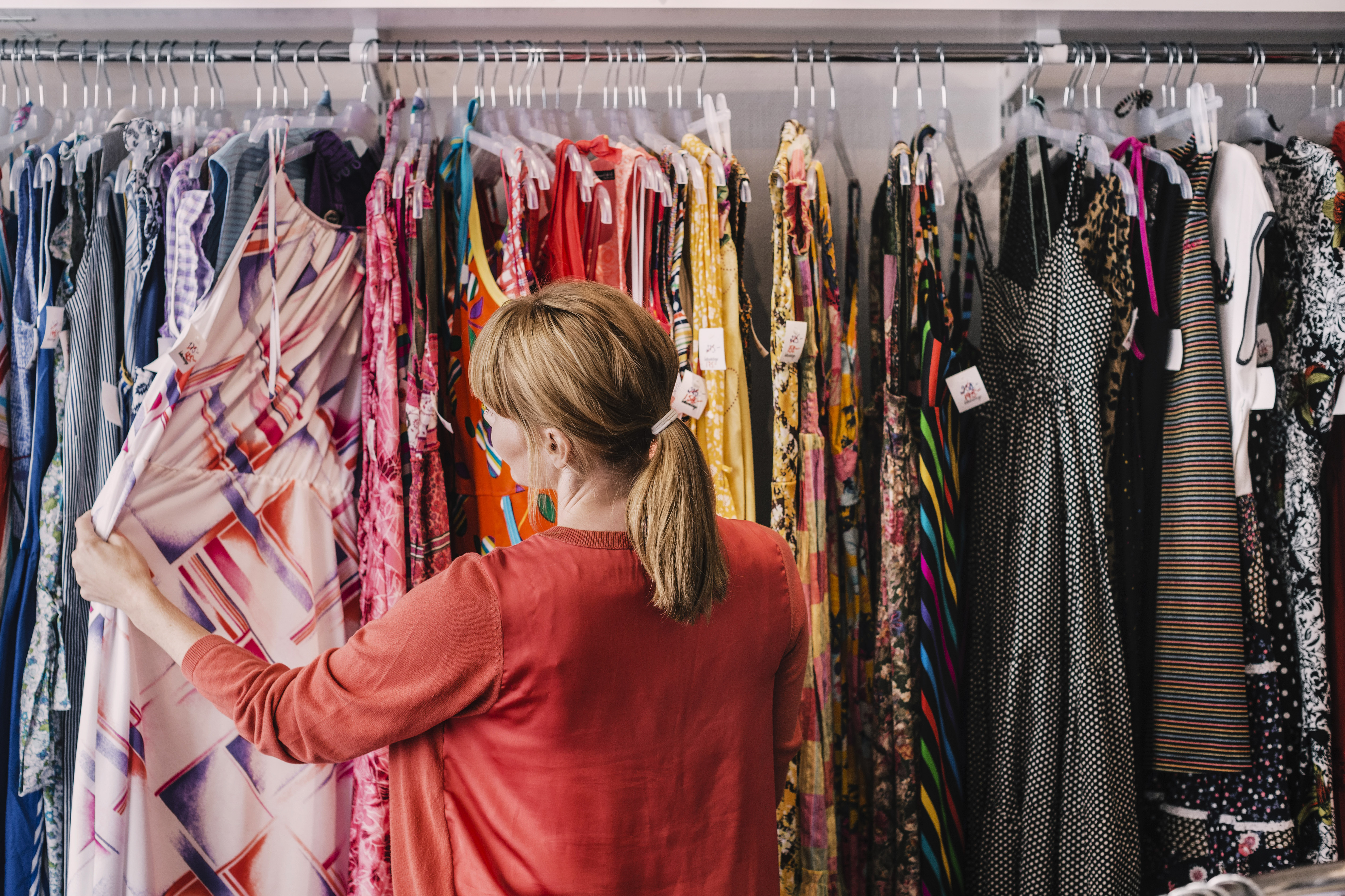 Una mujer mirando vestidos en una tienda | Foto: Getty Images