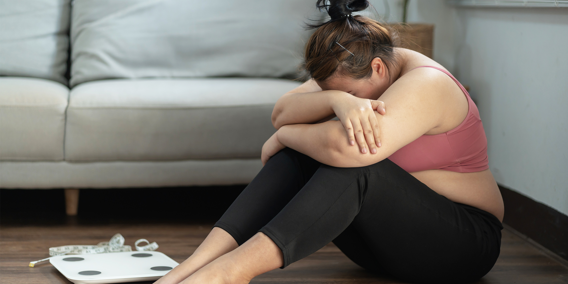 Una mujer llorando sentada junto a una báscula | Fuente: Shutterstock