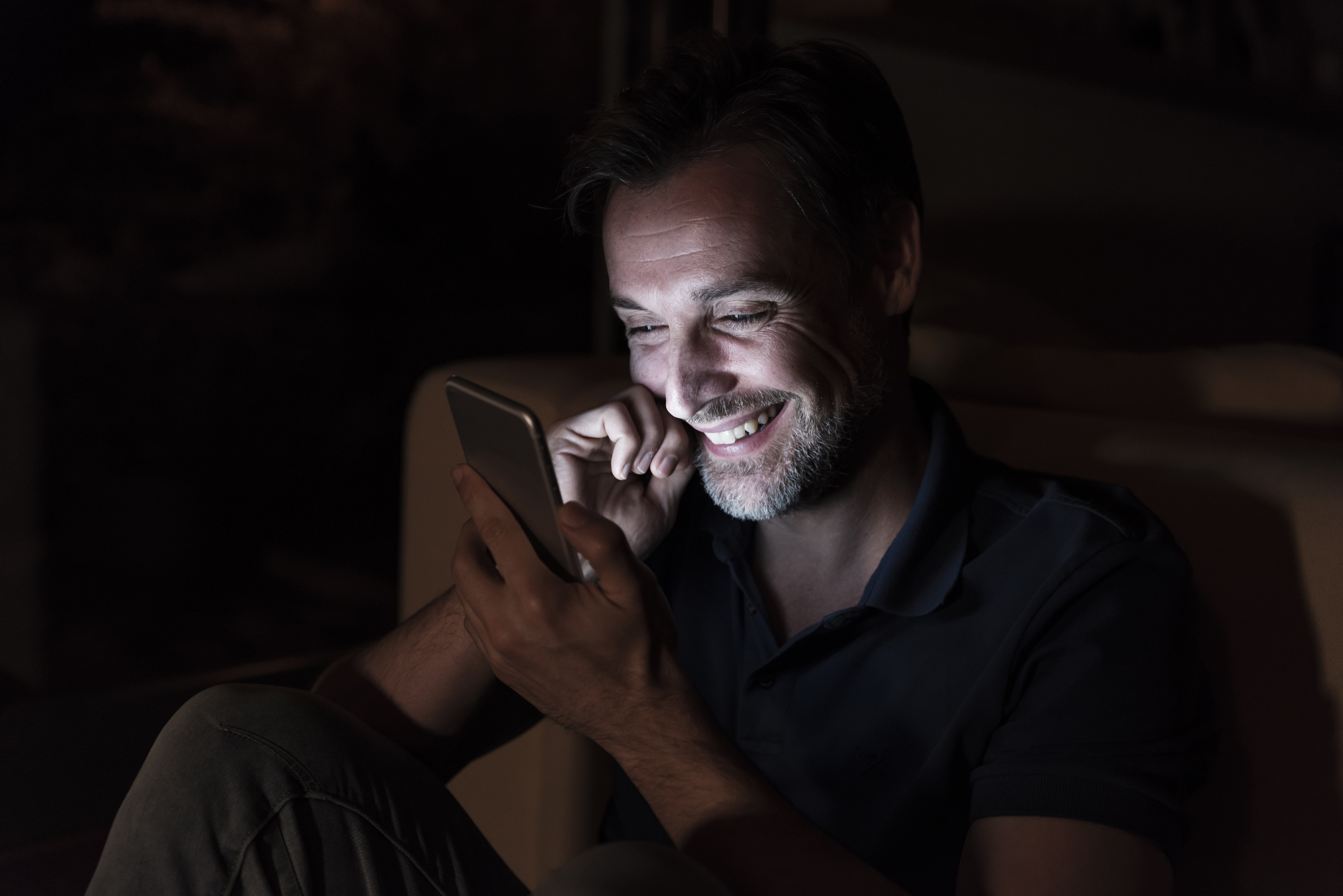 Hombre riendo mientras envía un mensaje de texto | Foto: Getty Images