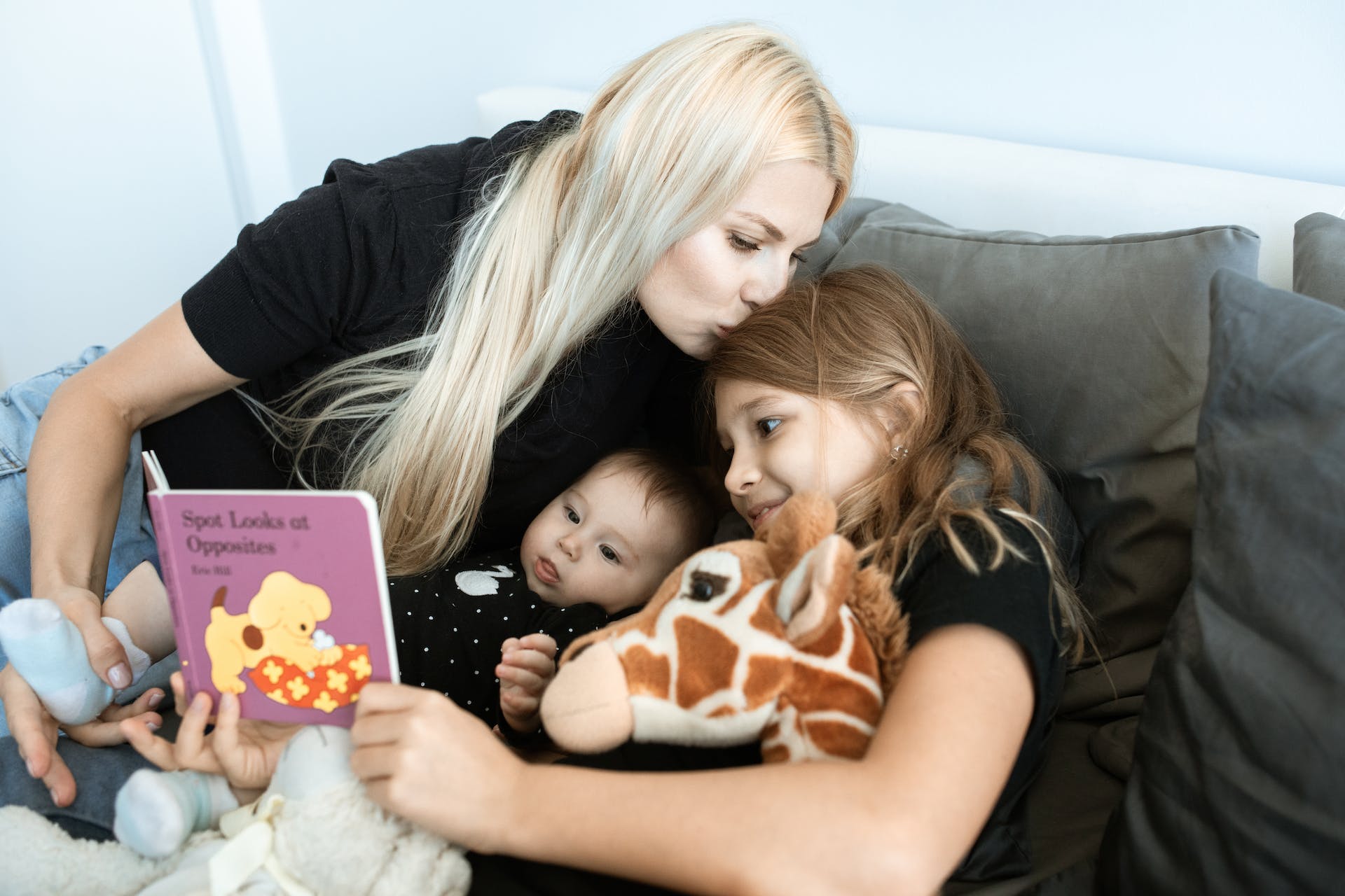 Una mujer creando lazos afectivos con sus dos hijos leyéndoles un libro | Fuente: Pexels