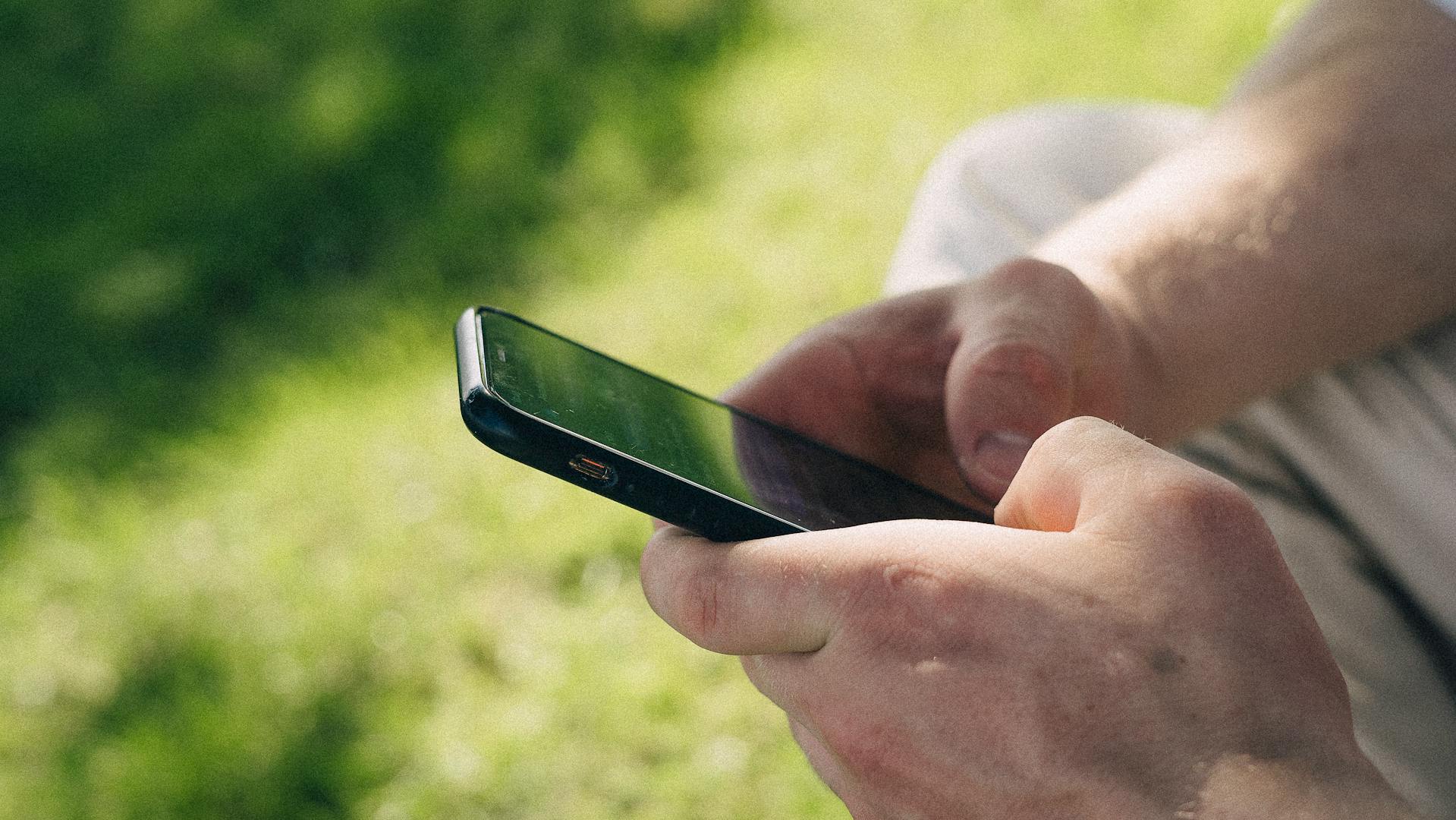 Un hombre utilizando su teléfono al aire libre | Fuente: Midjourney