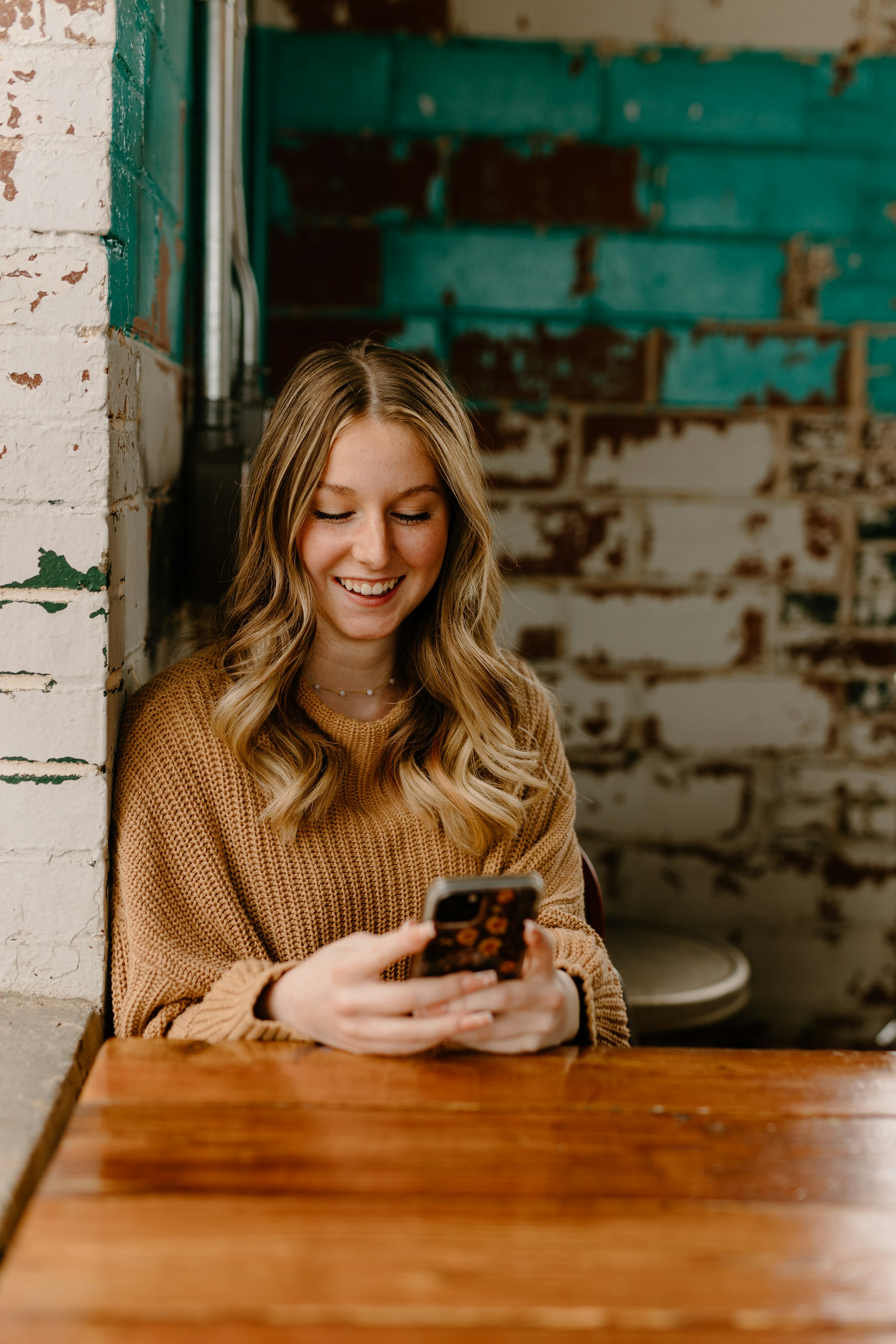 Una mujer sonríe mientras envía mensajes por el móvil | Fuente: Unsplash