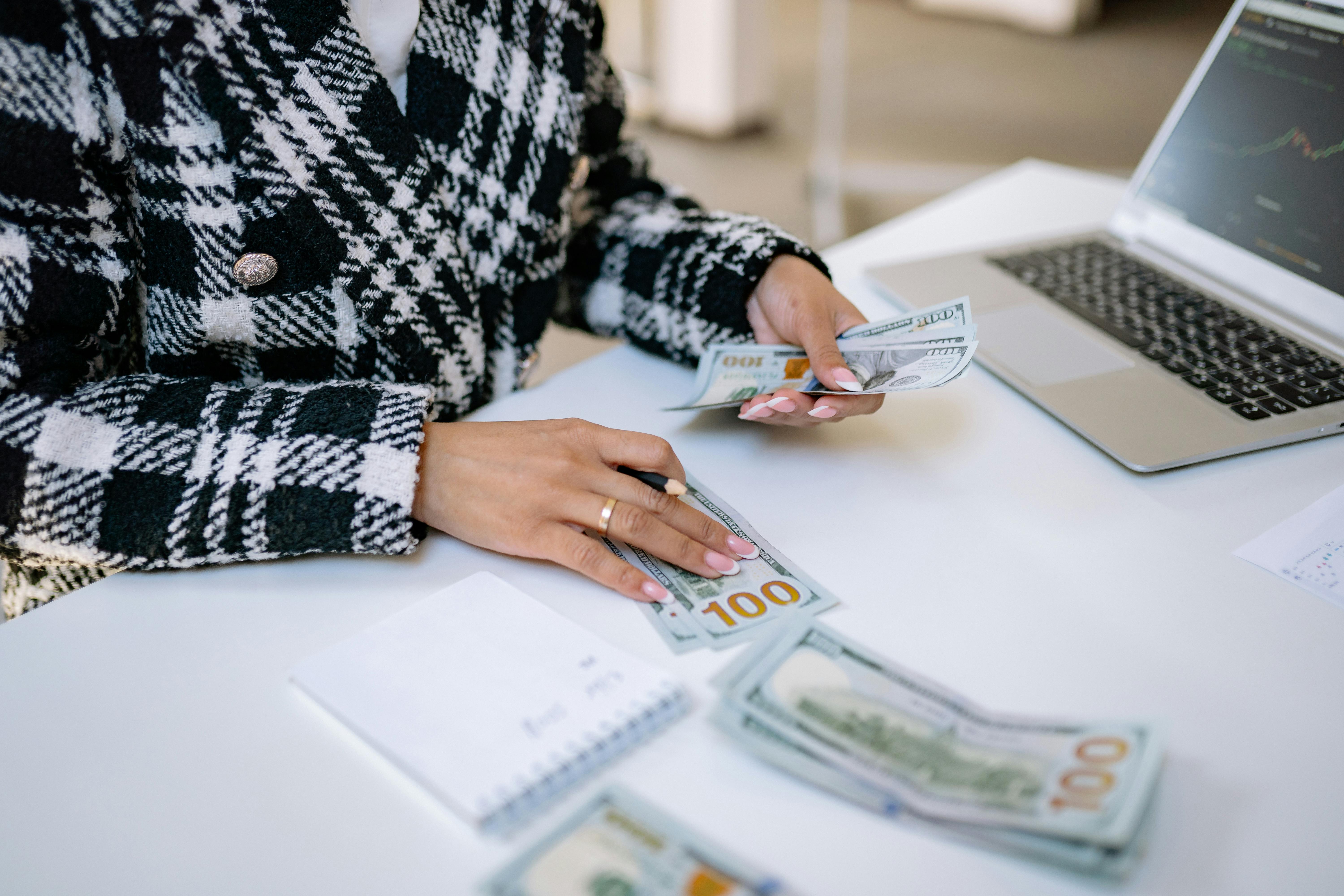 Una persona sentada en la mesa contando dinero | Fuente: Pexels