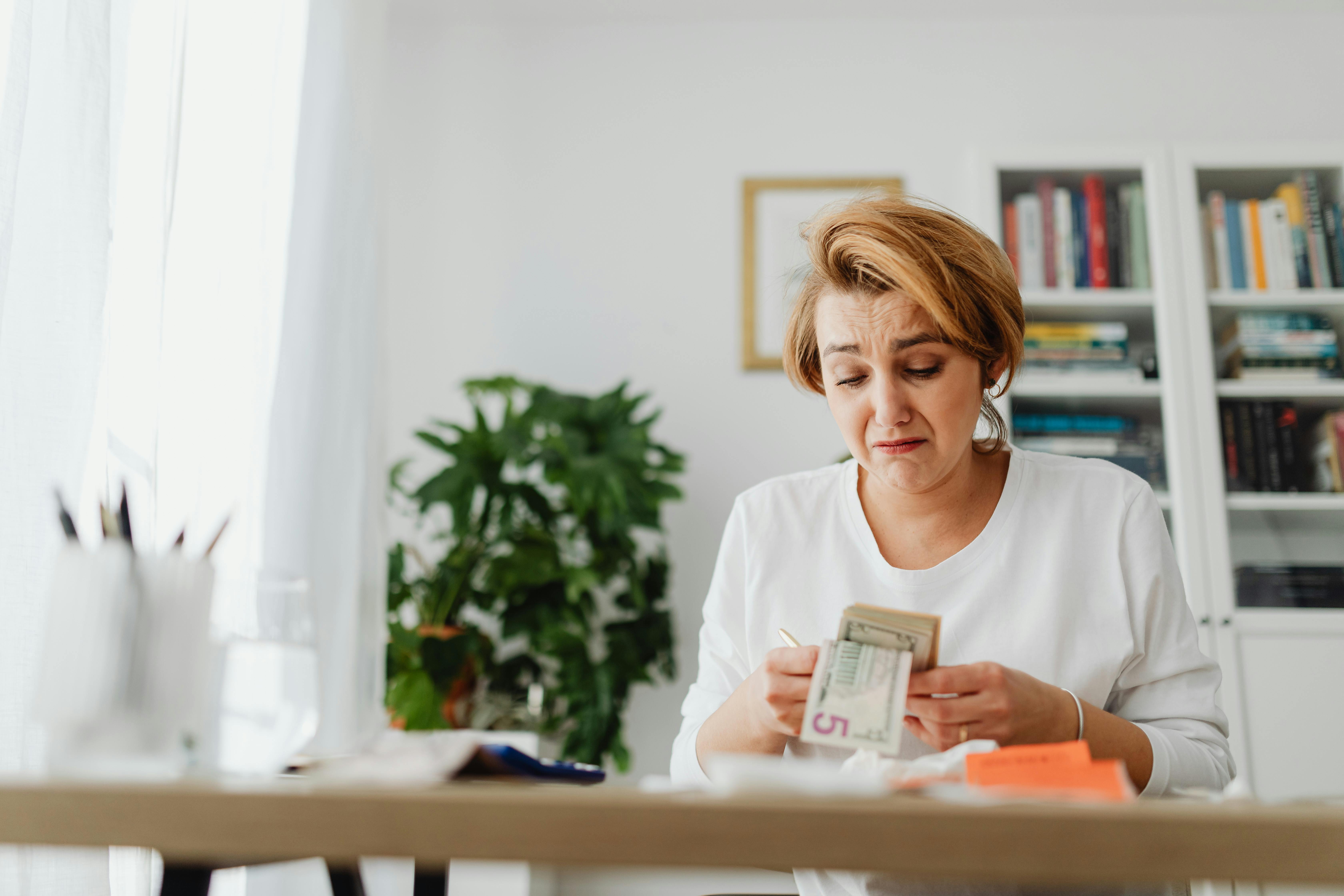 Una mujer triste contando dinero | Fuente: Pexels