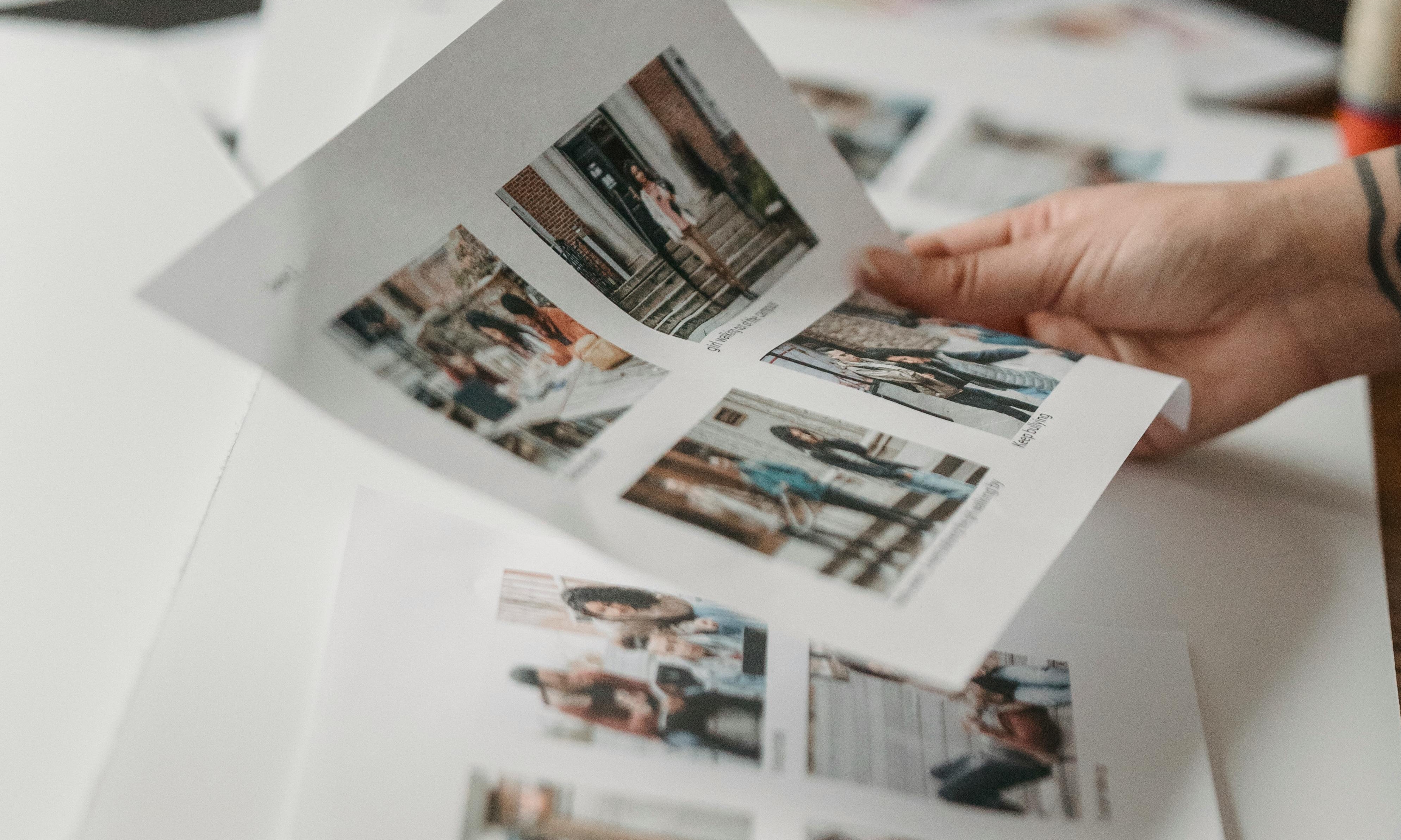 Una mano sujetando una página de fotos impresas | Fuente: Pexels