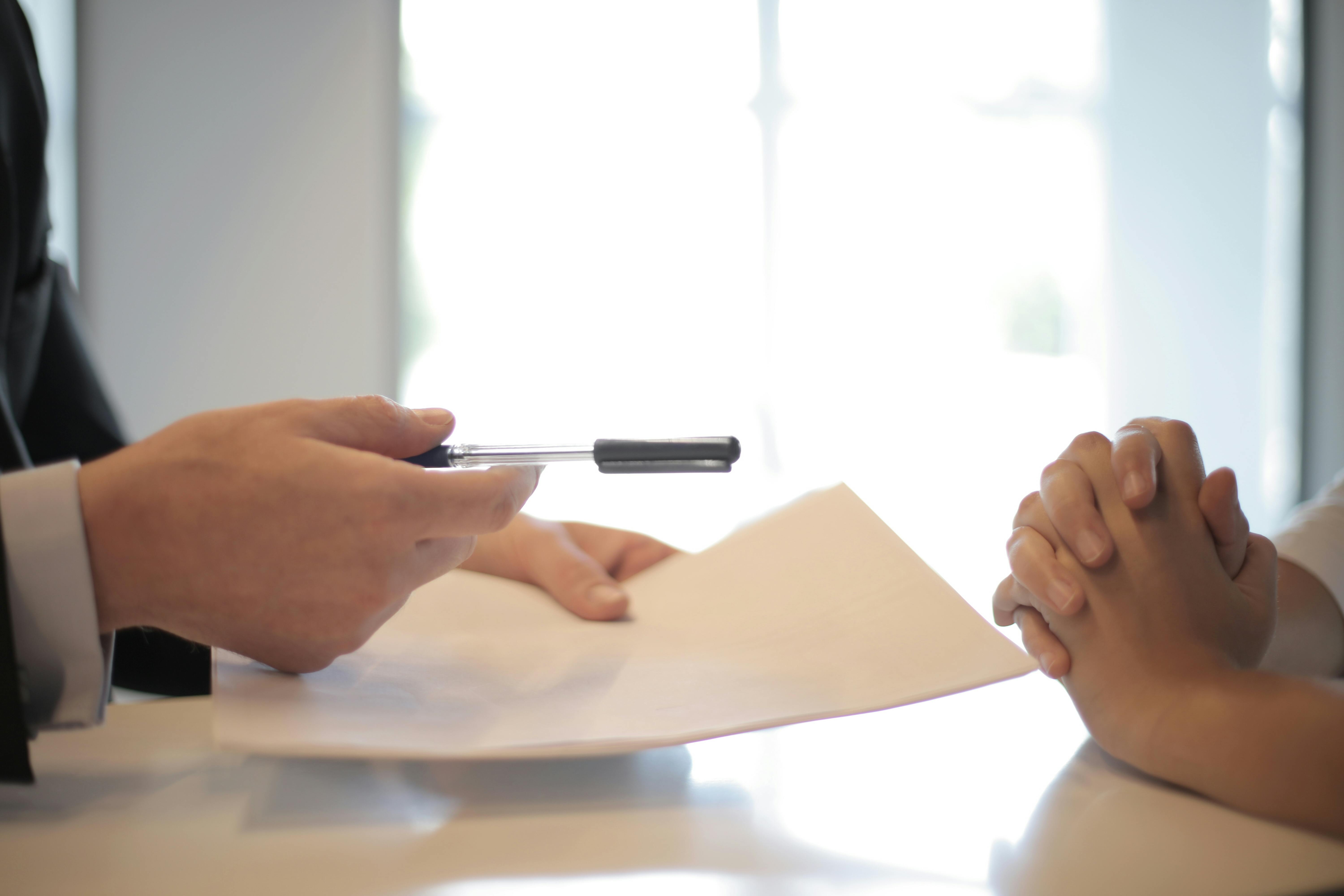 Una persona entregando un contrato y un bolígrafo | Foto: Pexels