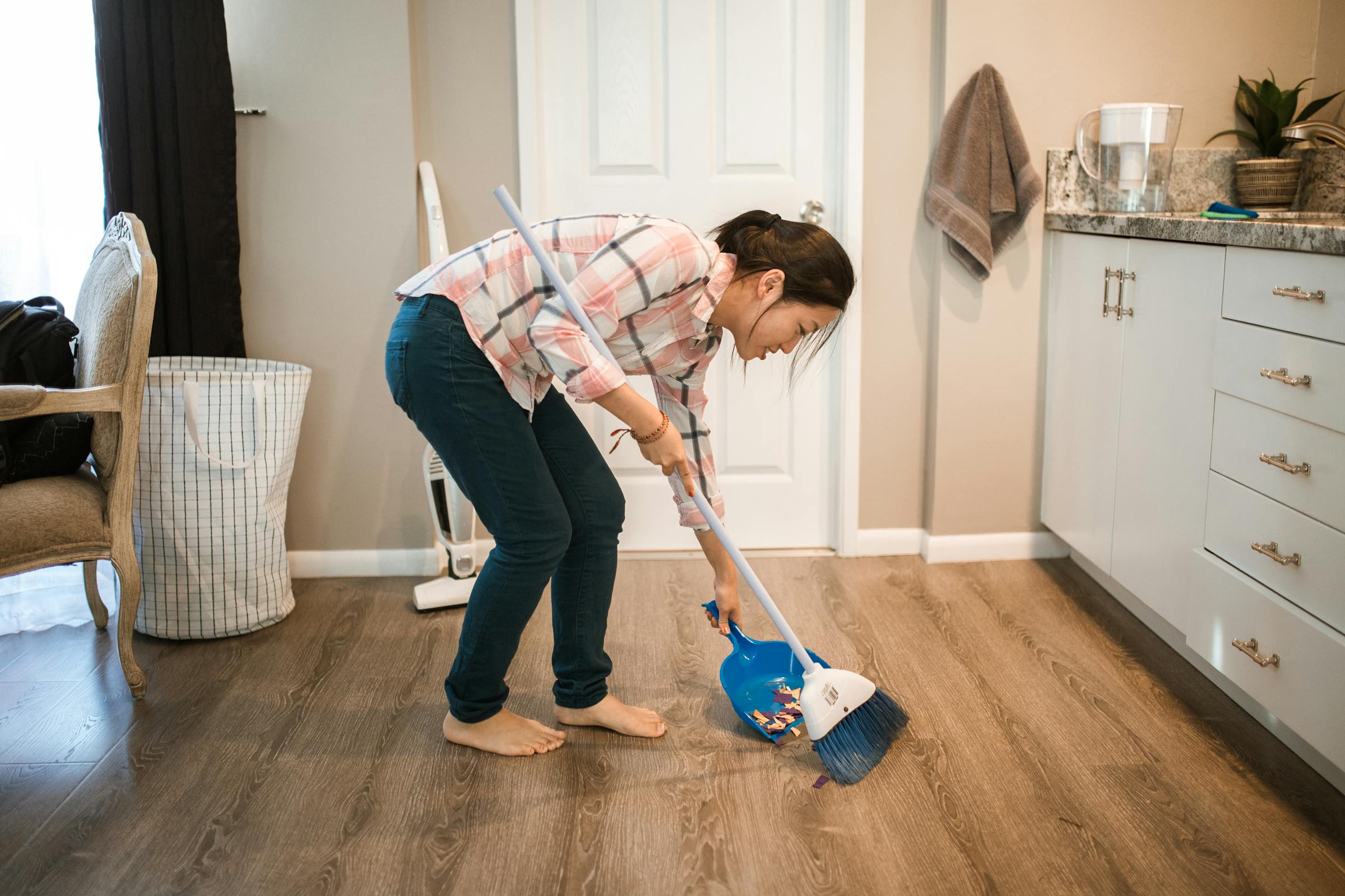 Una mujer barriendo mientras sonríe | Fuente: Pexels