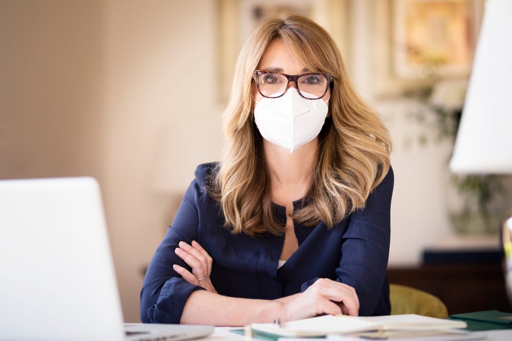 Mujer usando mascarilla facial mientras trabaja en su casa. | Foto: Shutterstock
