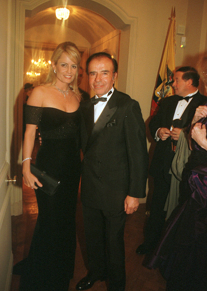 El expresidente argentino Carlos Menem y su pareja, Cecilia Bolocco, ex Miss Universo, salen de una fiesta en la residencia de la Embajada de Ecuador en Washington D. C., el 19 de enero de 2001 | Fuente: Getty Images