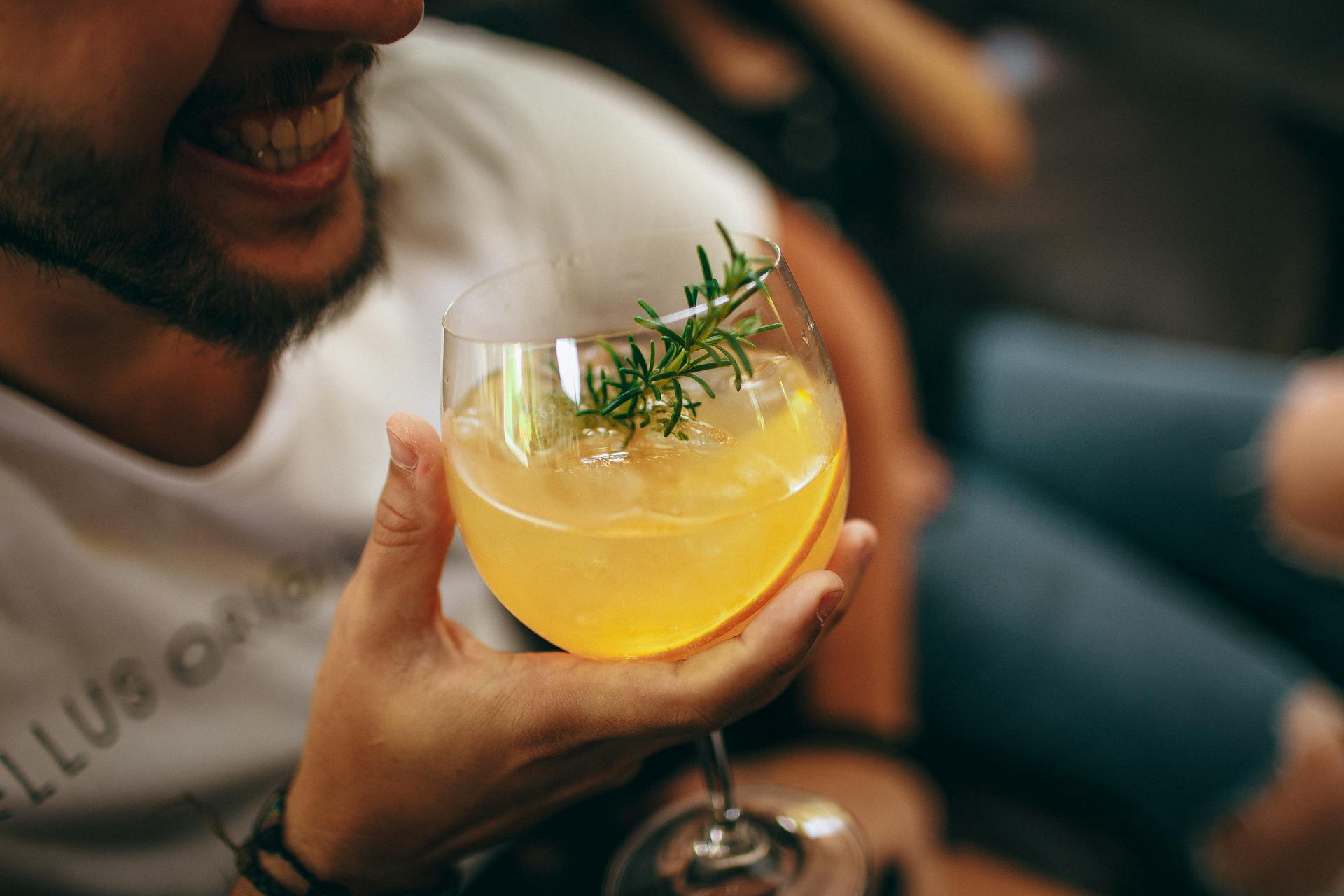 Un hombre sonriente con una bebida en la mano | Fuente: Pexels