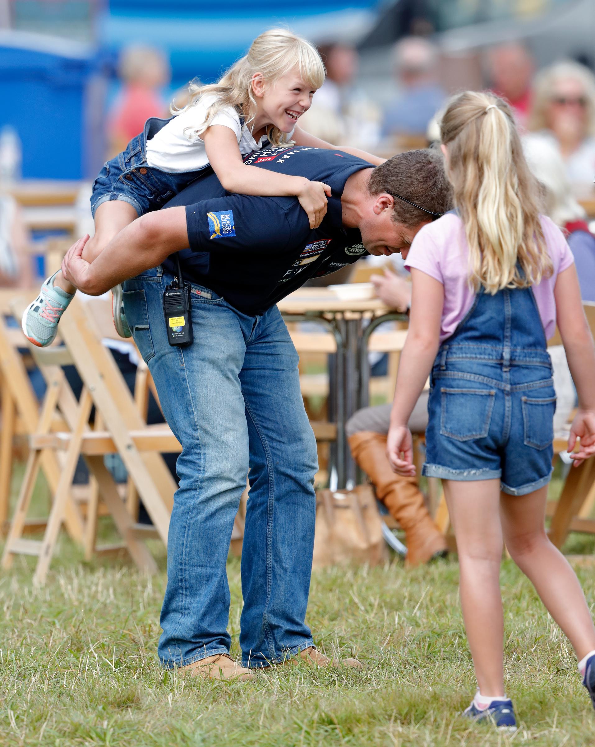 Savannah Phillips (d) mira como Peter Phillips le da a su hija Isla Phillips un caballito en el día 1 del 2019 Festival of British Eventing en Gatcombe Park el 2 de agosto de 2019 en Stroud, Inglaterra | Fuente: Getty Images