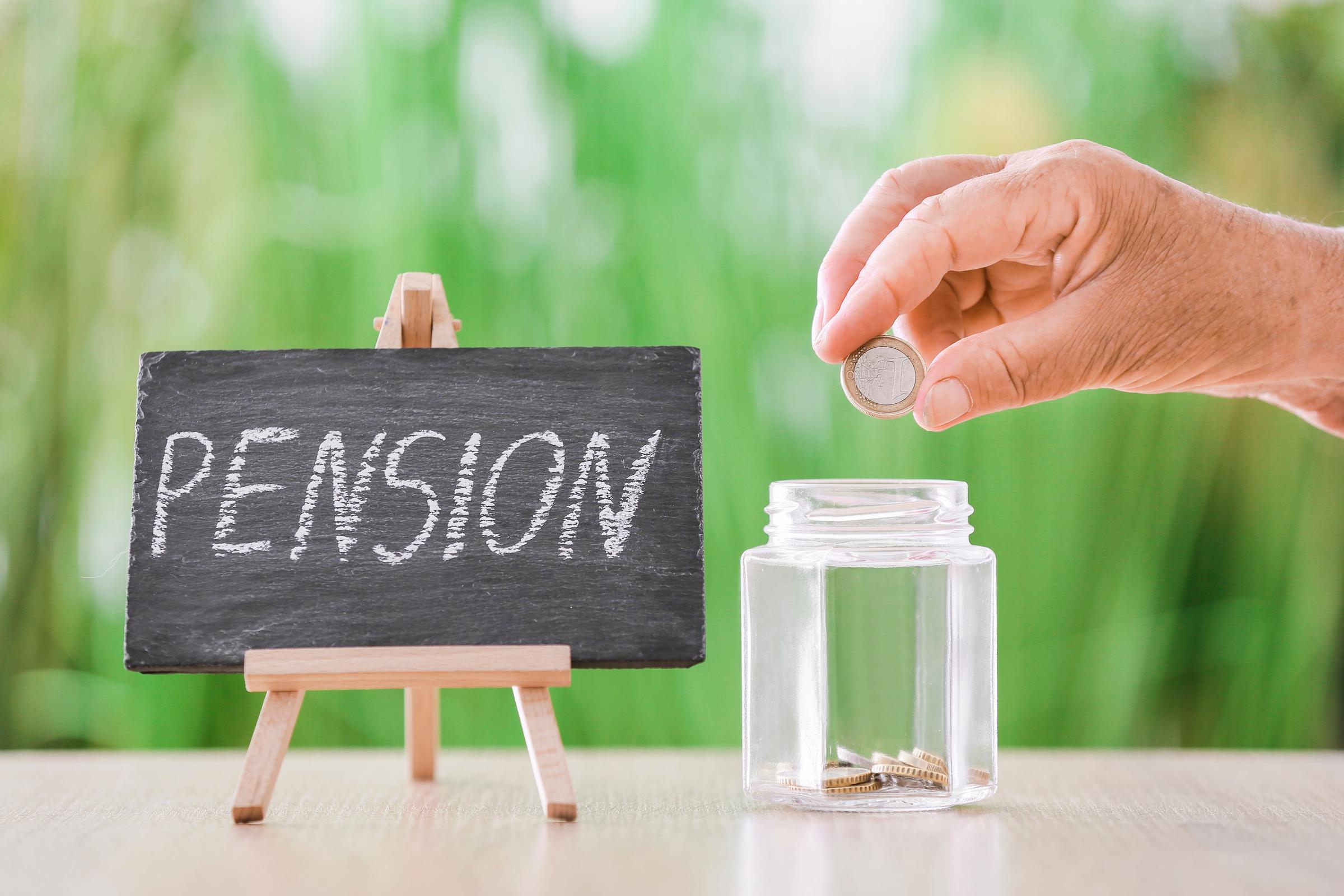 Mano de una persona mayor metiendo monedas en un tarro | Fuente: Shutterstock