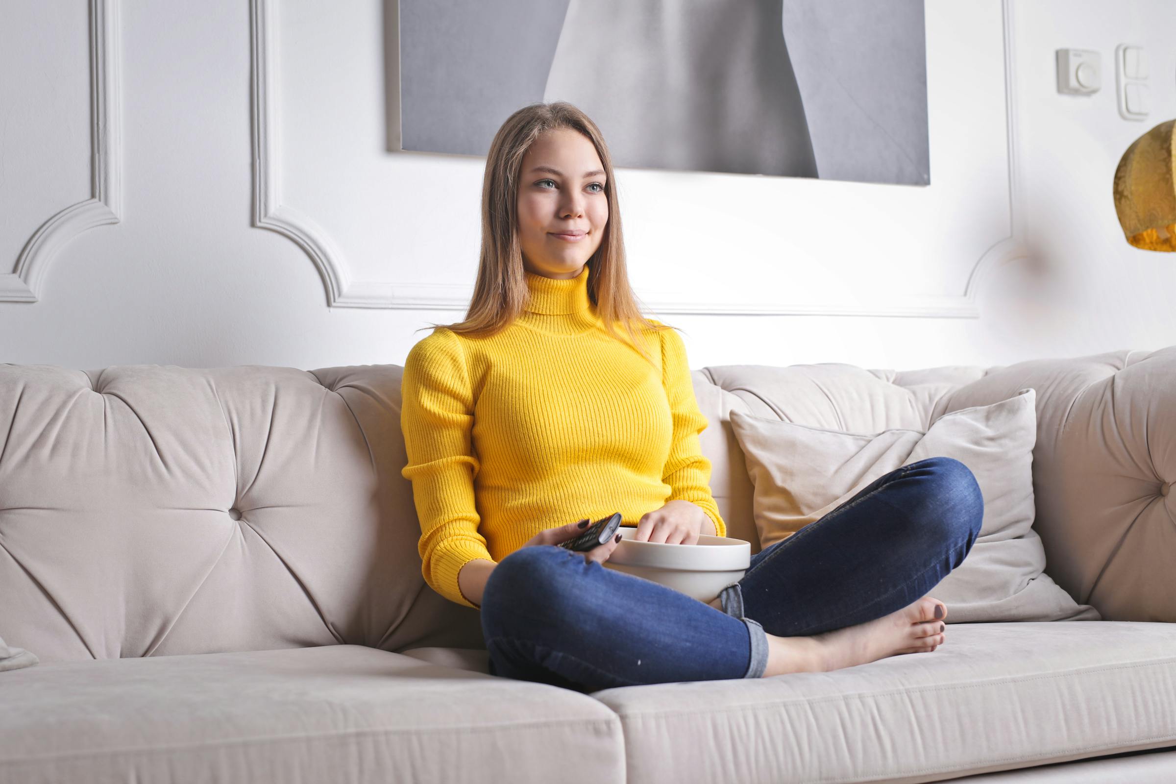 Mujer sentada en un sofá con palomitas | Fuente: Pexels