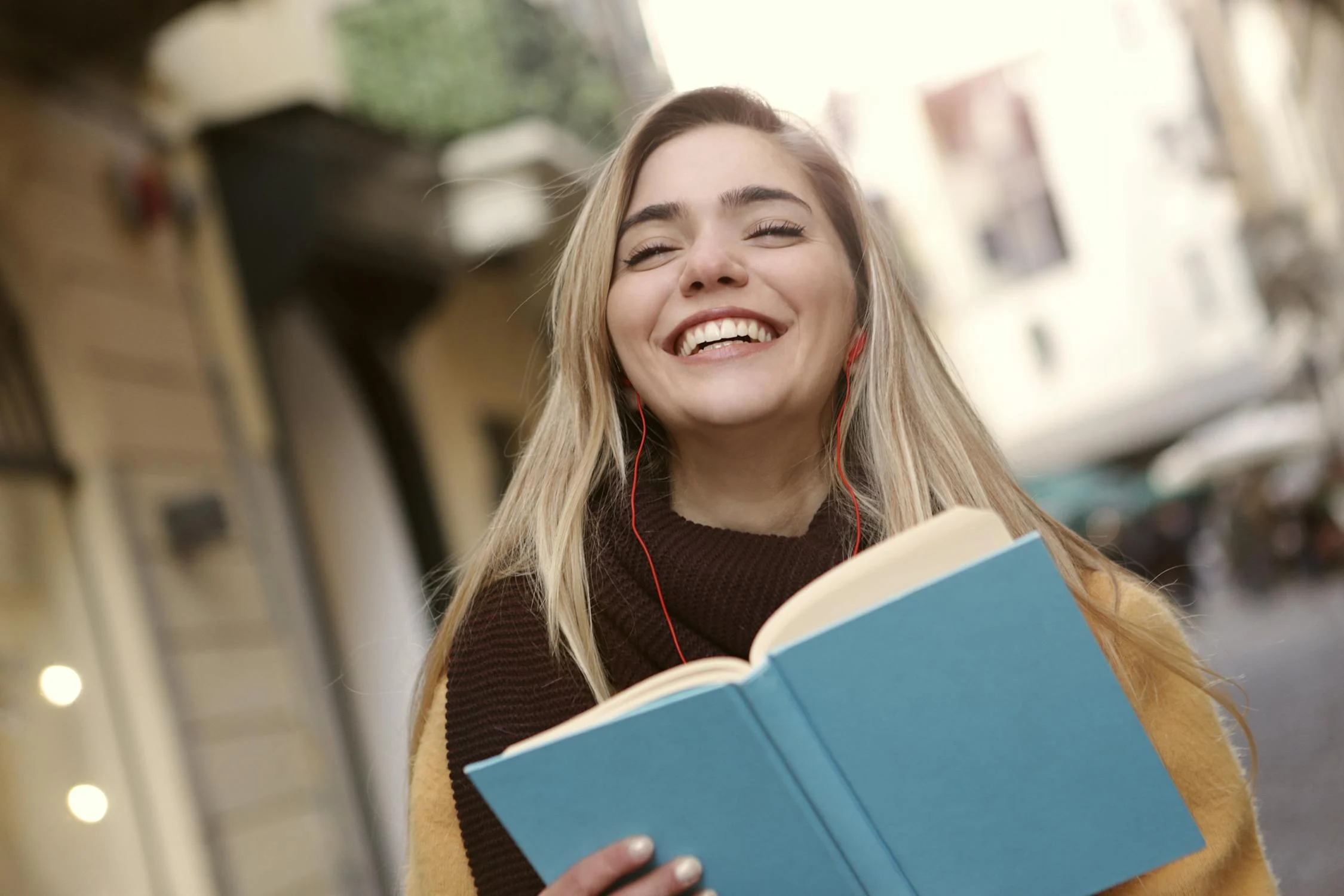 Una mujer sonriente con un libro | Fuente: Pexels