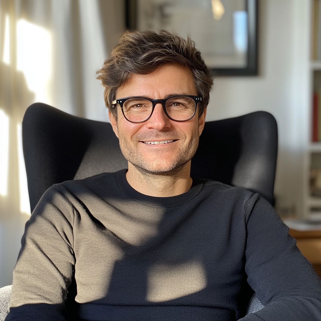 Un hombre sonriente vestido con un jersey negro y sentado en un sillón | Fuente: Midjourney