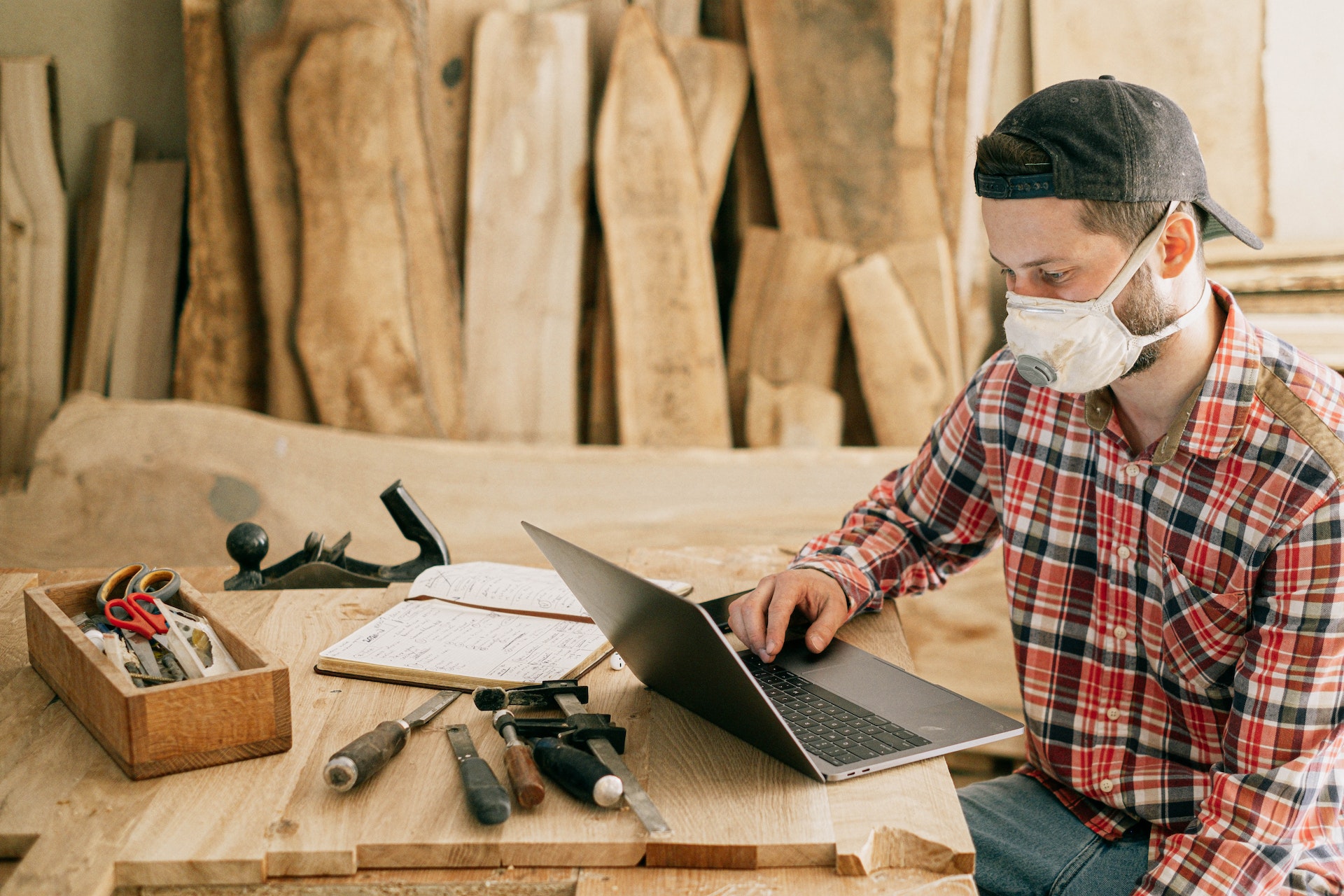 Una persona utilizando un ordenador portátil en un taller de madera | Fuente: Pexels