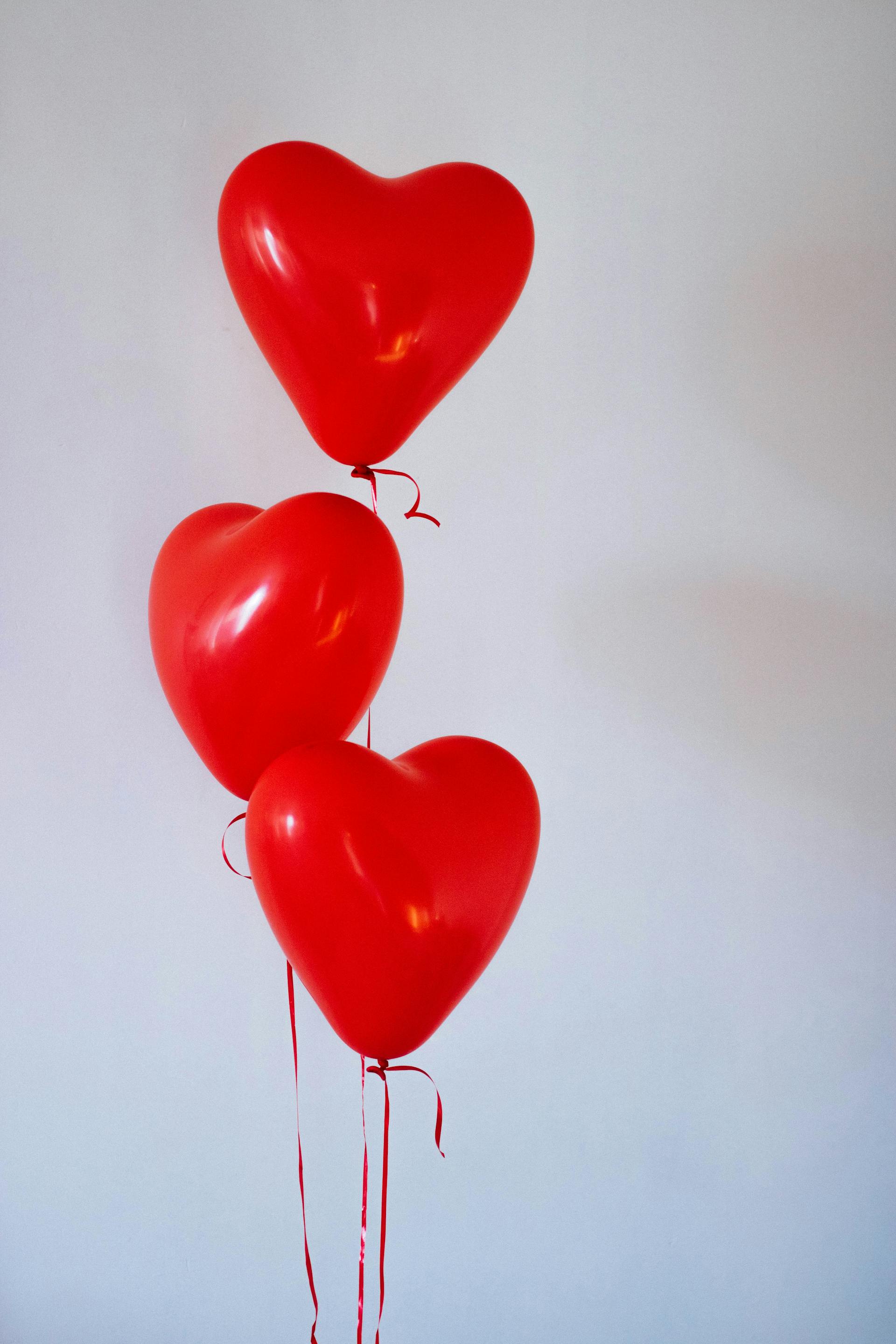 Tres globos rojos en forma de corazón | Foto: Pexels
