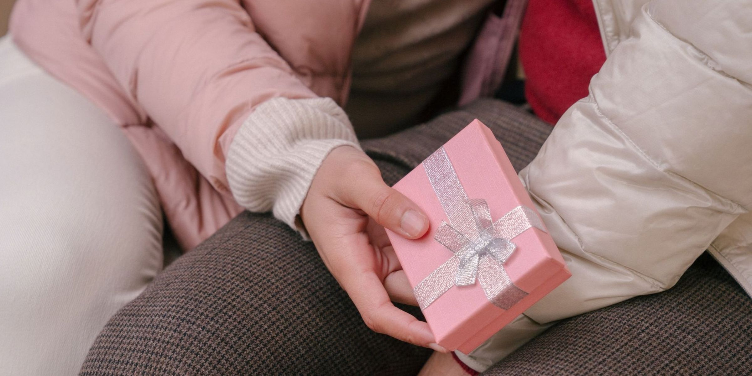 Un primo piano che mostra una persona con in mano una confezione regalo rosa con un nastro argentato | Fonte: Pexels