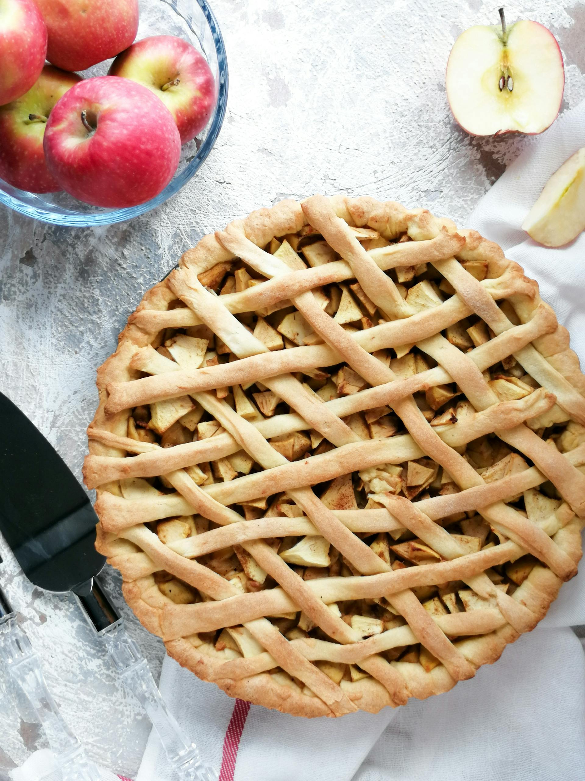 Una tarta de manzana sobre una mesa con un cuenco de manzanas | Fuente: Pexels