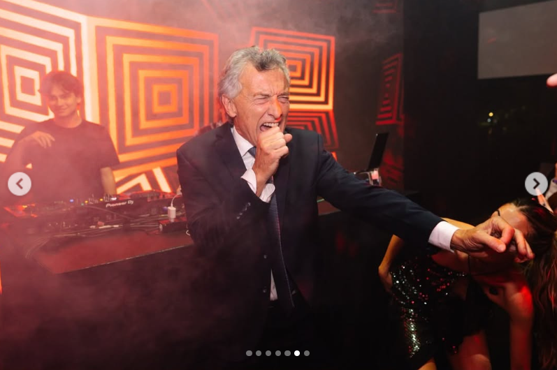 Mauricio Macri canta con euforia apretando el puño frente a la cabina del DJ, animando la fiesta mientras baila junto a los invitados bajo las luces de colores de la ambientación. | Fuente: Instagram/mauriciomacri