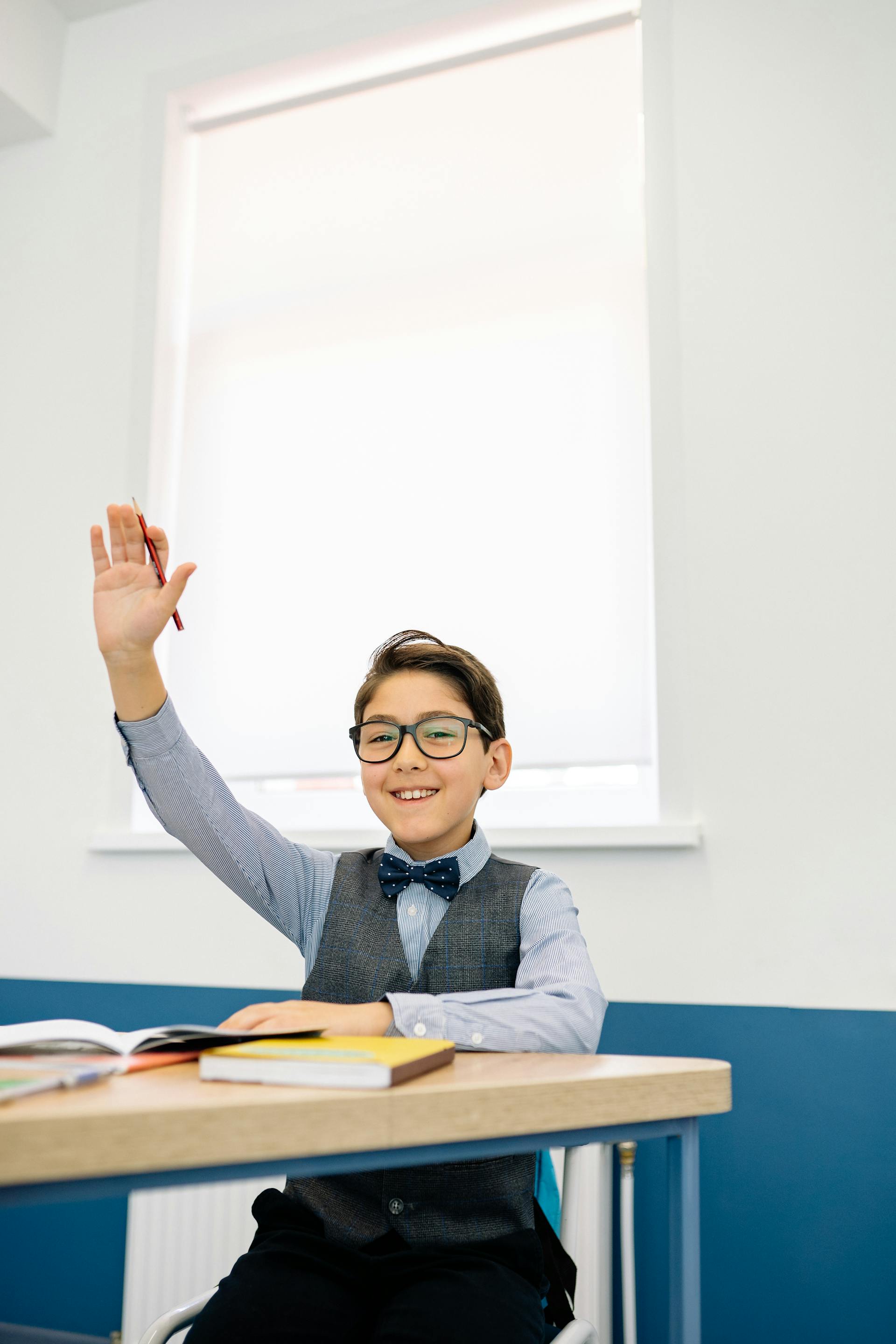 Un niño levantando la mano en una clase | Fuente: Pexels