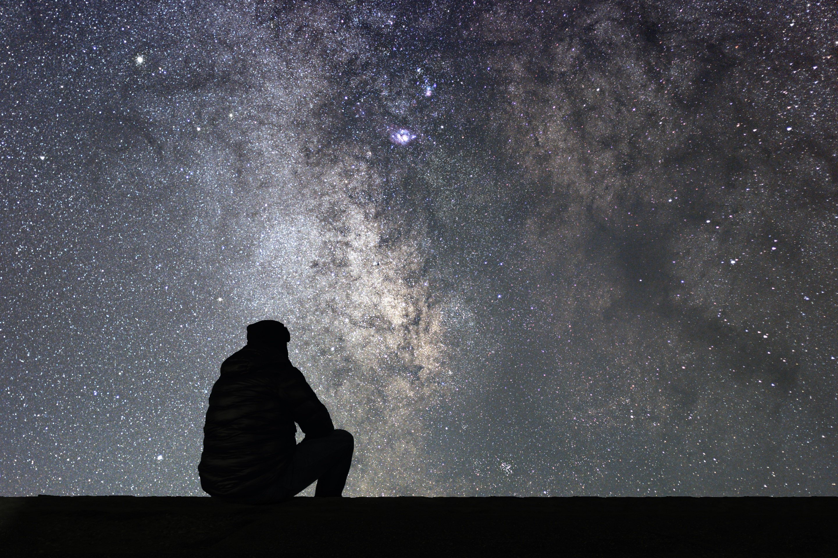 Hombre reflexiona mirando el cielo nocturno estrellado || Fuente: Shutterstock