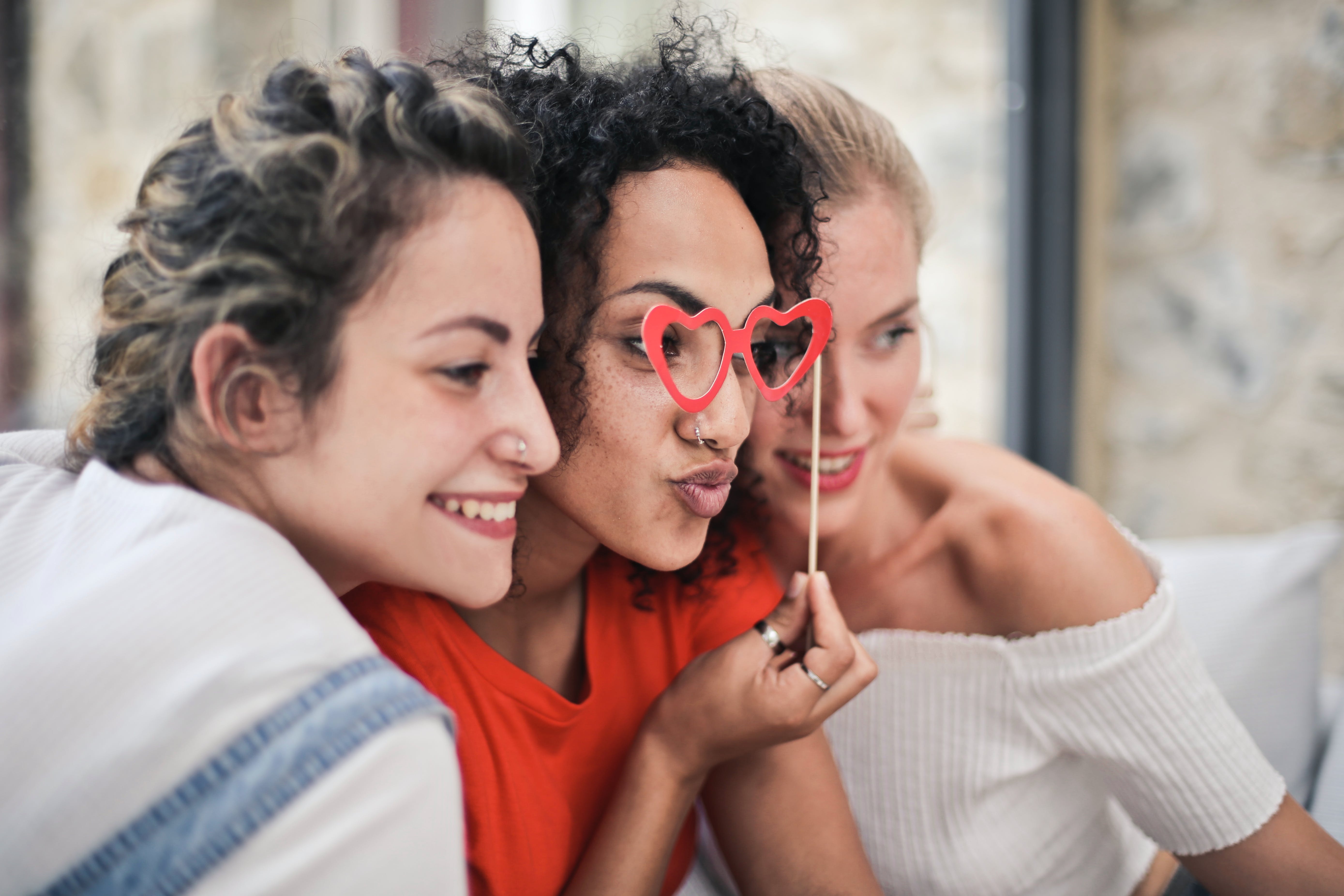 Tres mujeres felices sonriendo mientras estrechan lazos | Foto: Pexels