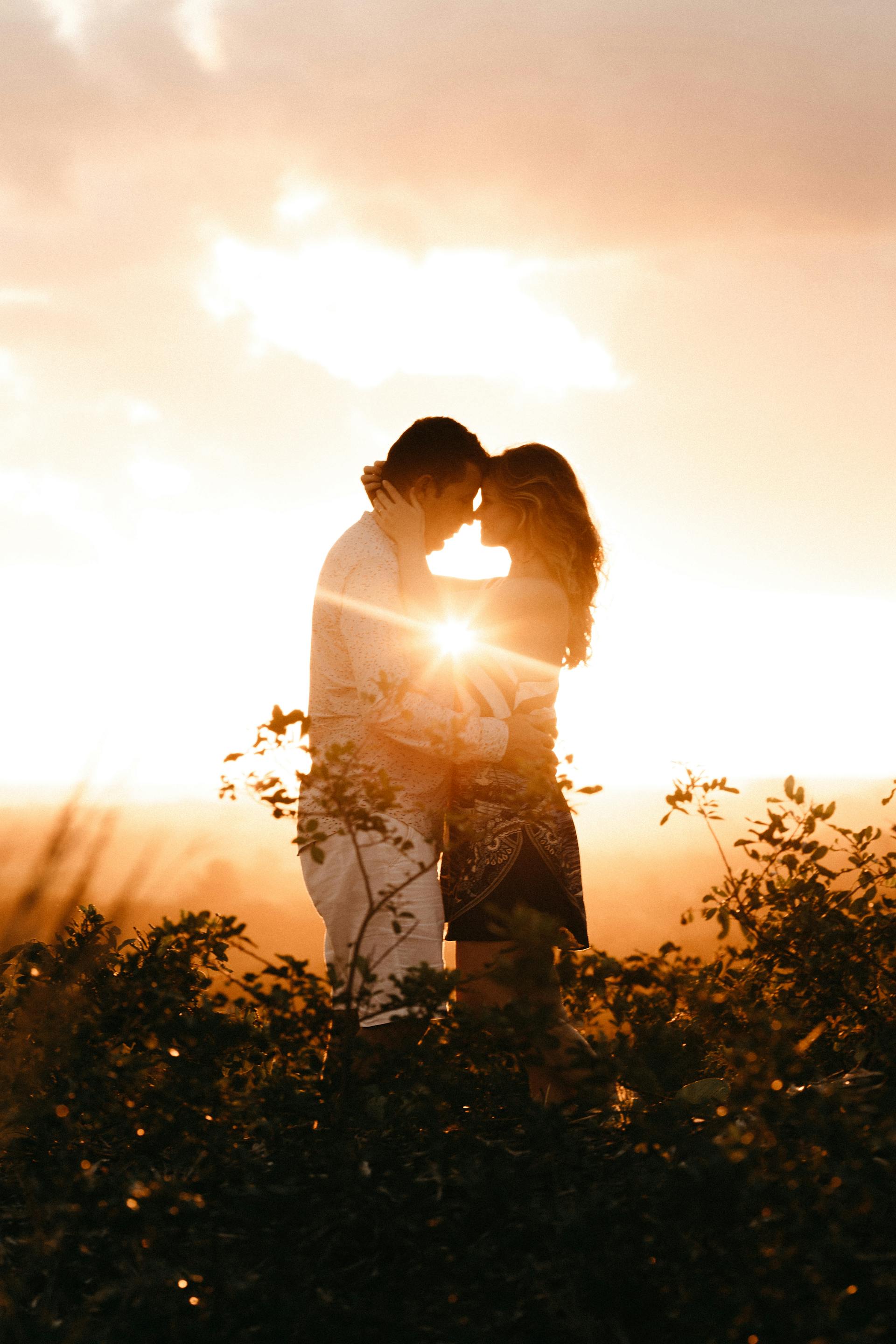 Una pareja abrazándose en un campo durante la hora dorada | Foto: Pexels