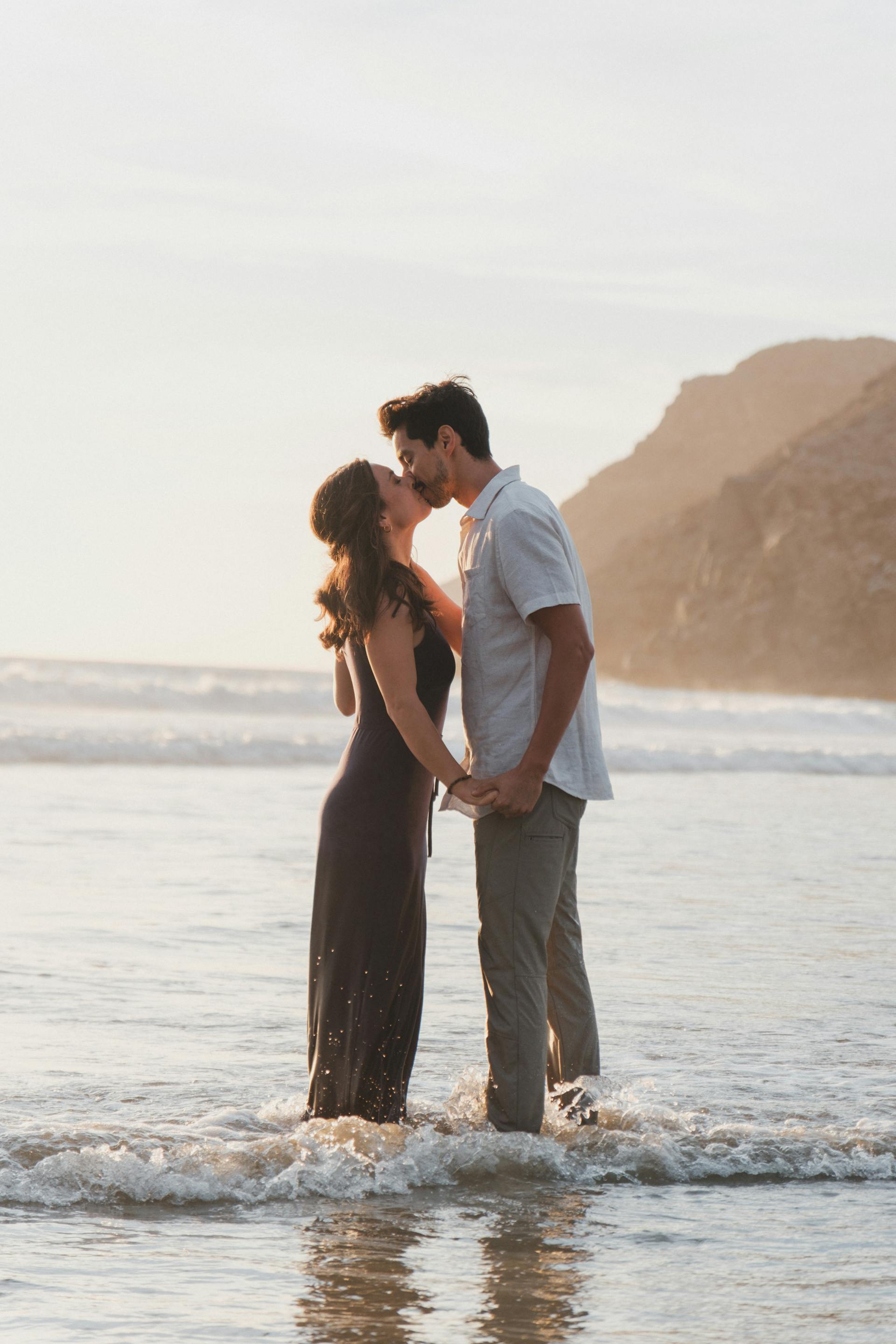 Una pareja besándose con los tobillos metidos en el mar | Fuente: Pexels