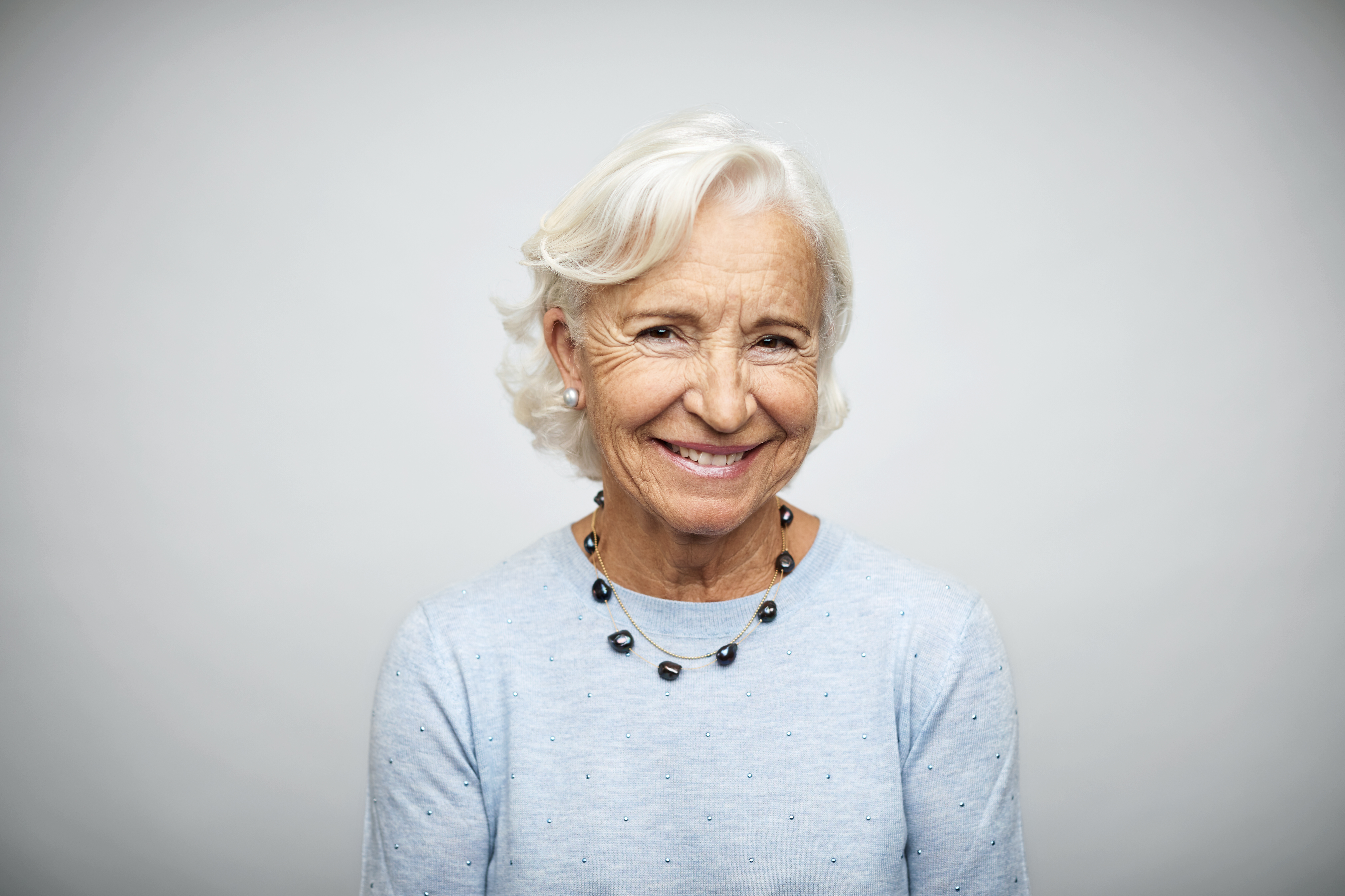 Anciana empresaria sonriendo sobre fondo blanco | Fuente: Getty Images