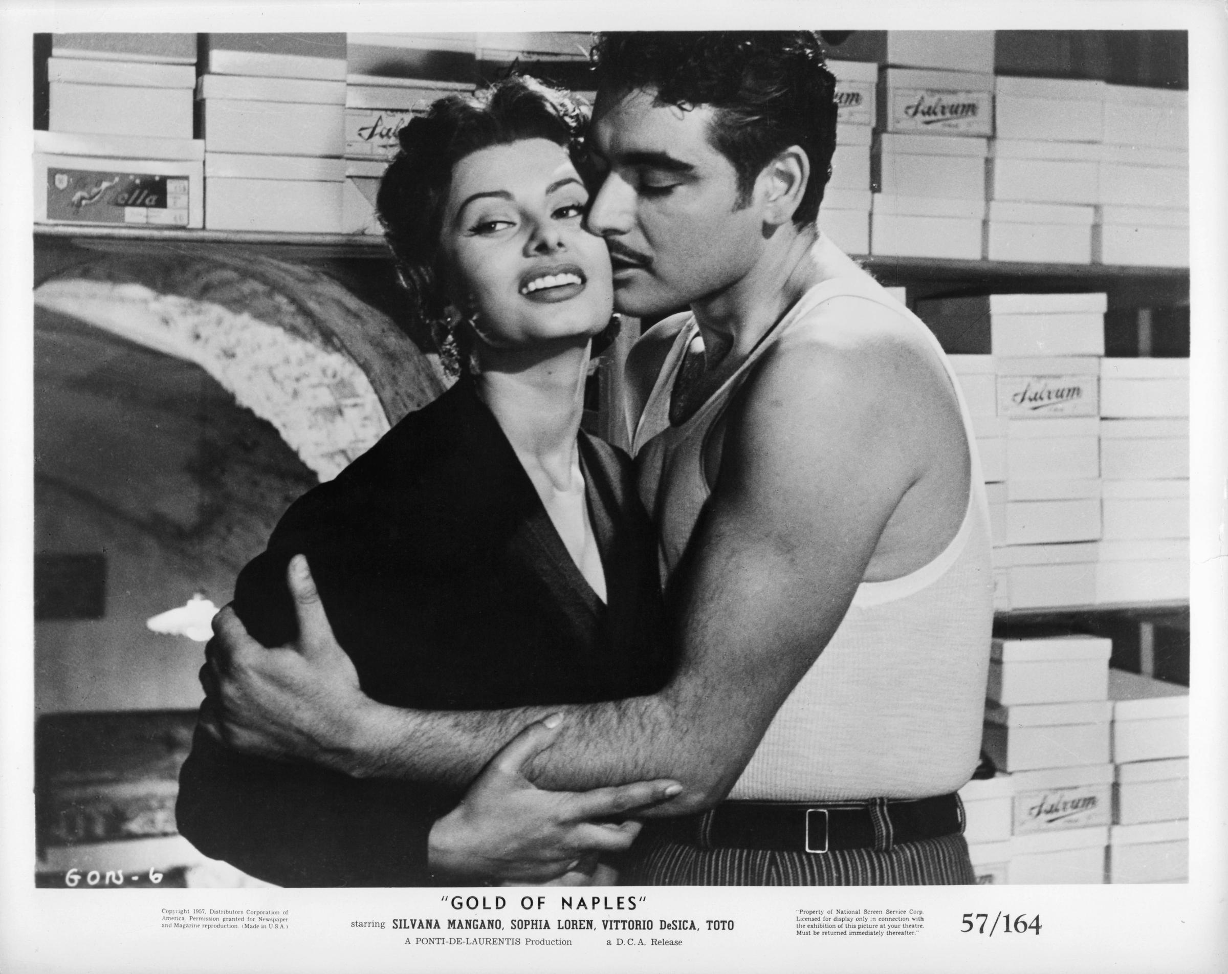 Sophia Loren mira hacia otro lado mientras un hombre la besa en la mejilla en una escena de la película 'El oro de Nápoles', 1954.