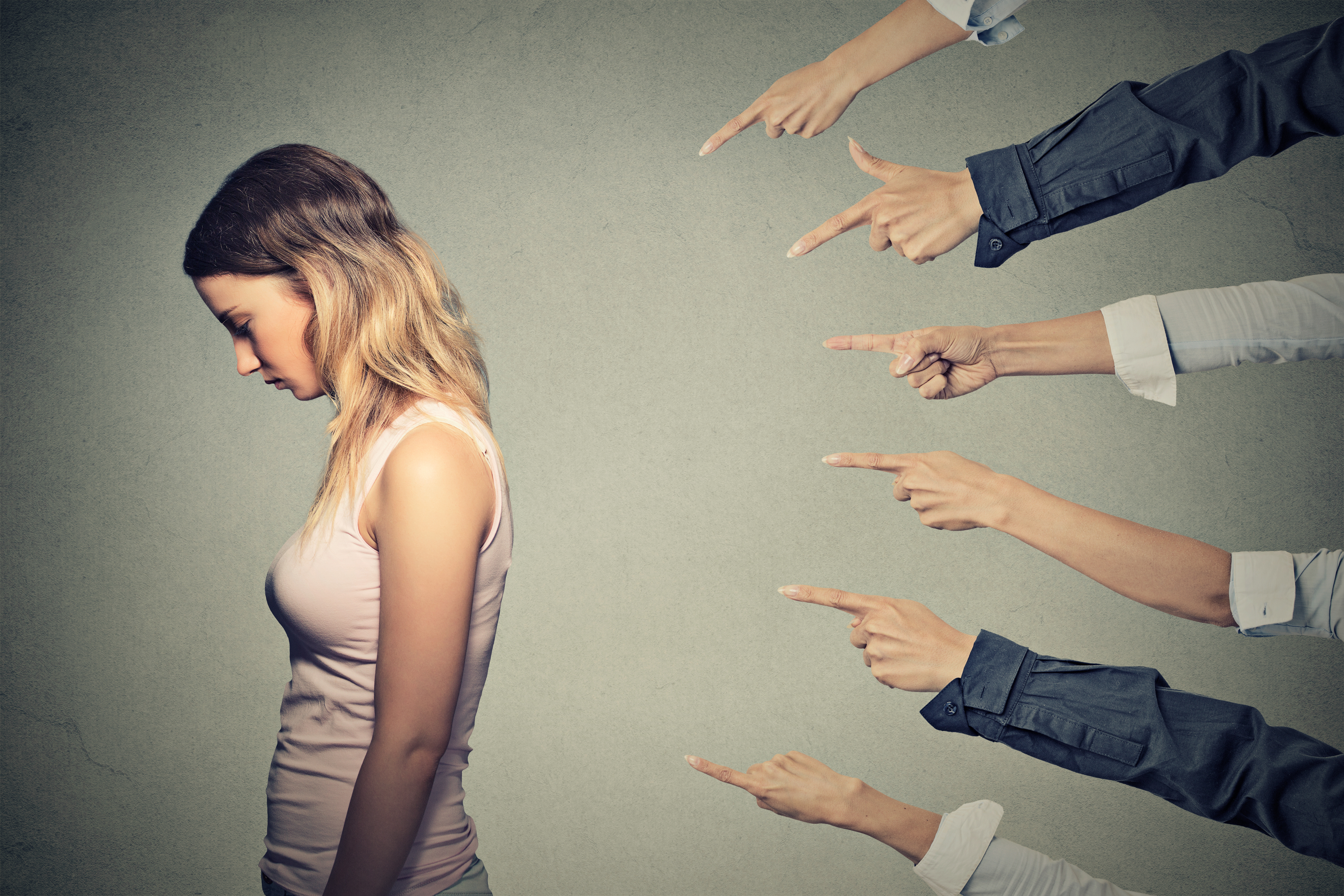 Mujer disgustada con muchas manos señalándola | Foto: Shutterstock