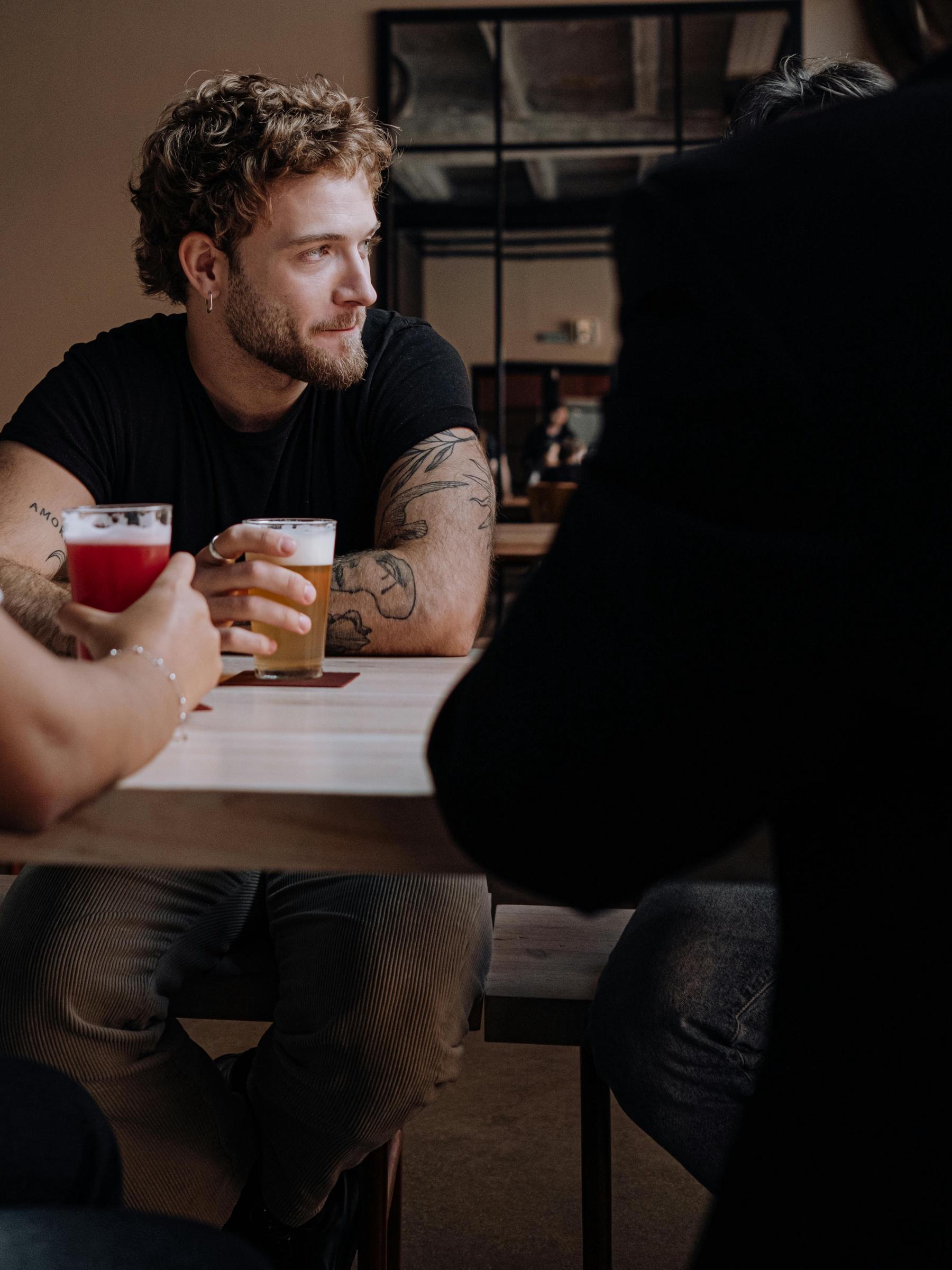 Un hombre mirando a un lado, sentado con una cerveza a mano | Fuente: Pexels