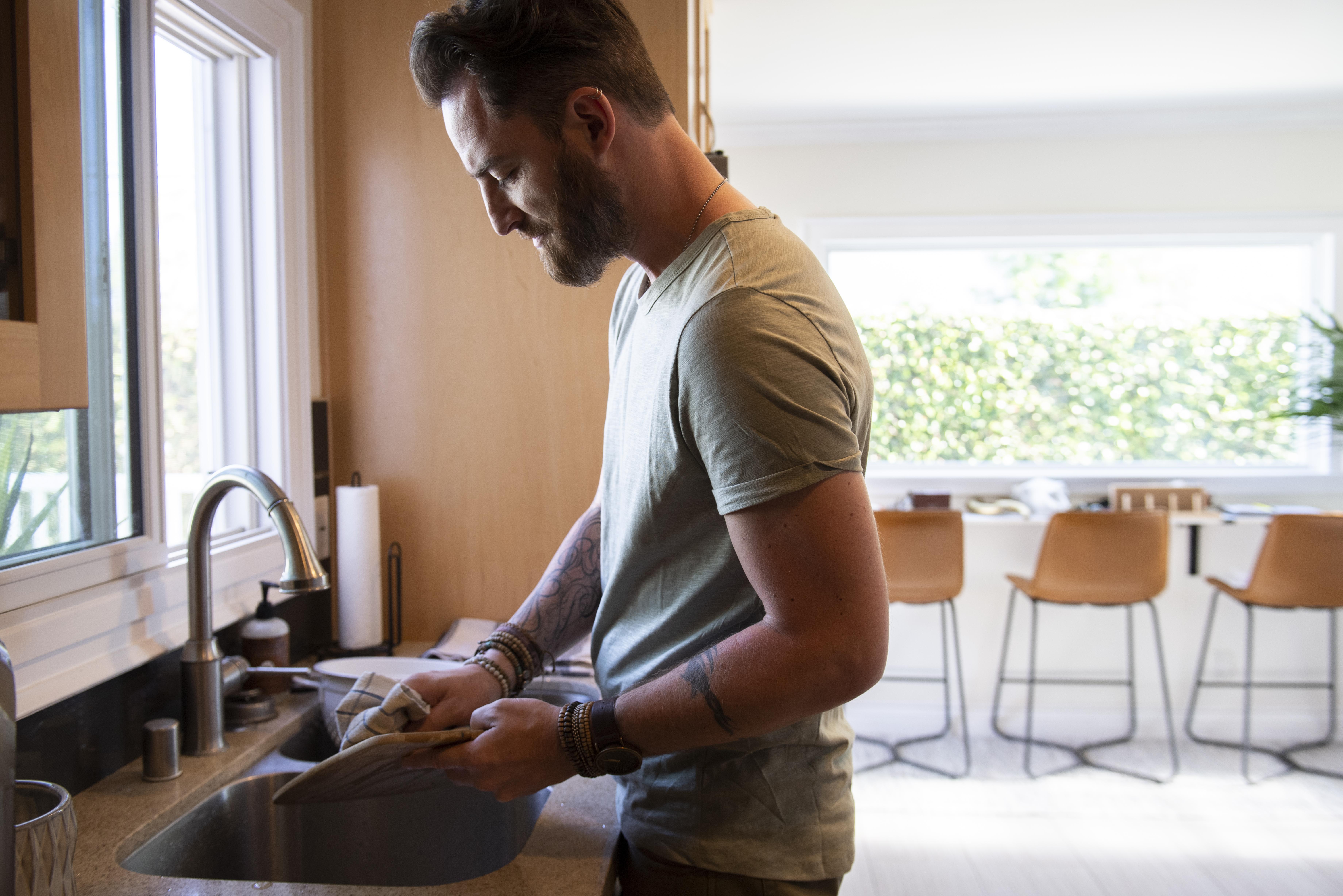 Hombre lavando platos en la cocina | Fuente: Freepik