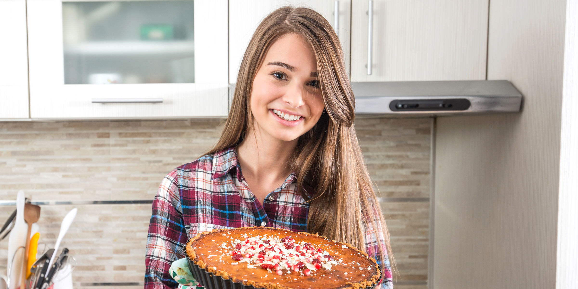 Una mujer sonriente con una tarta en la mano | Fuente: Shutterstock