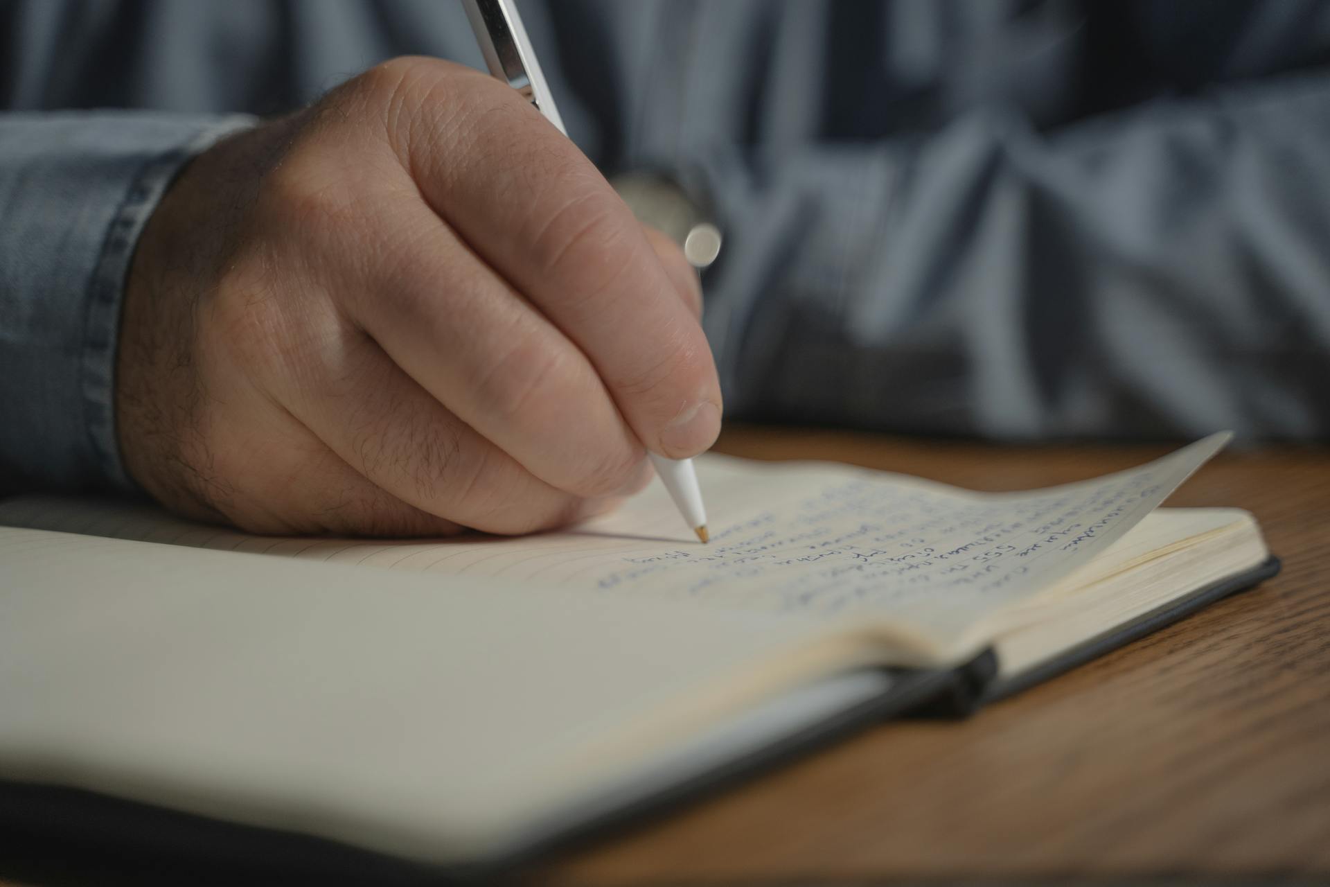 Un hombre escribiendo en su cuaderno | Fuente: Pexels