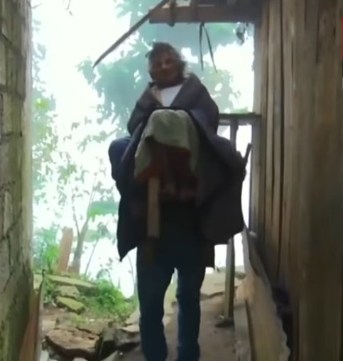 Castro traslada a una anciana enferma sobre una silla en su espalda. | Foto: Captura YouTube/Milenio
